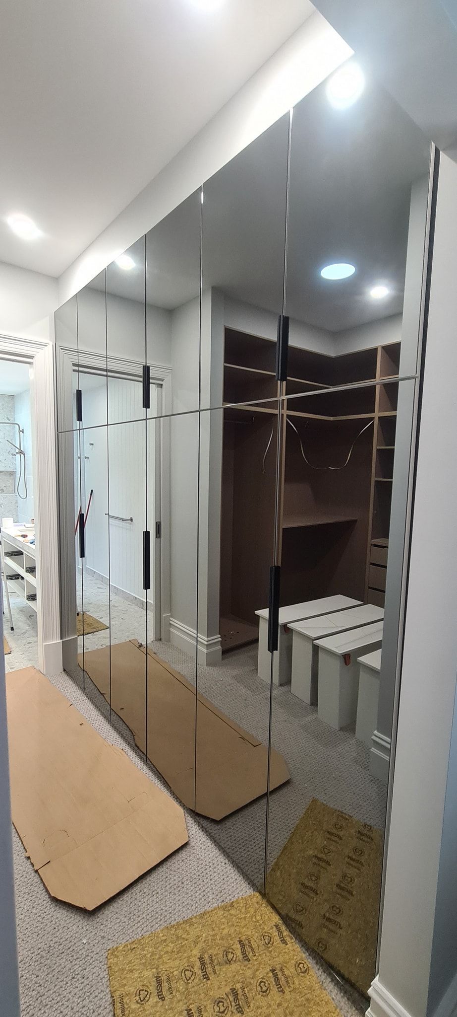 A walk in closet with a large mirror on the wall.