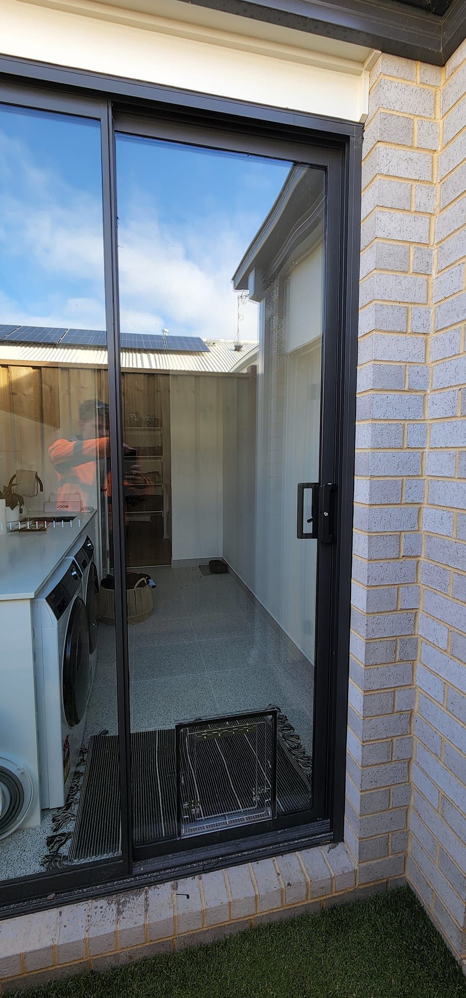A sliding glass door with a reflection of a house in it.