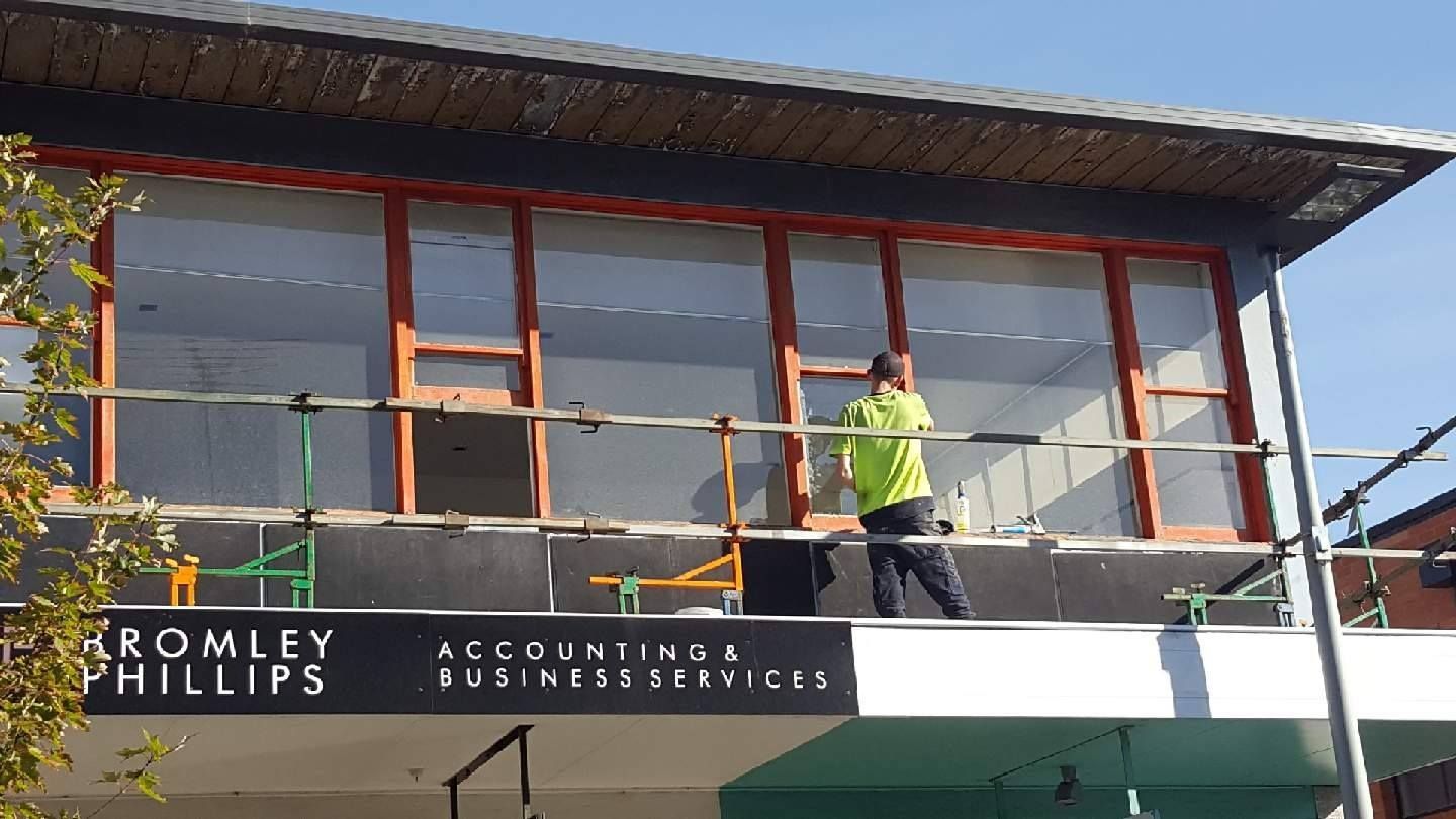 A man is standing on top of a building with a sign that says kromley phillips