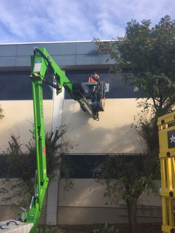 A man is working on the side of a building with a green crane