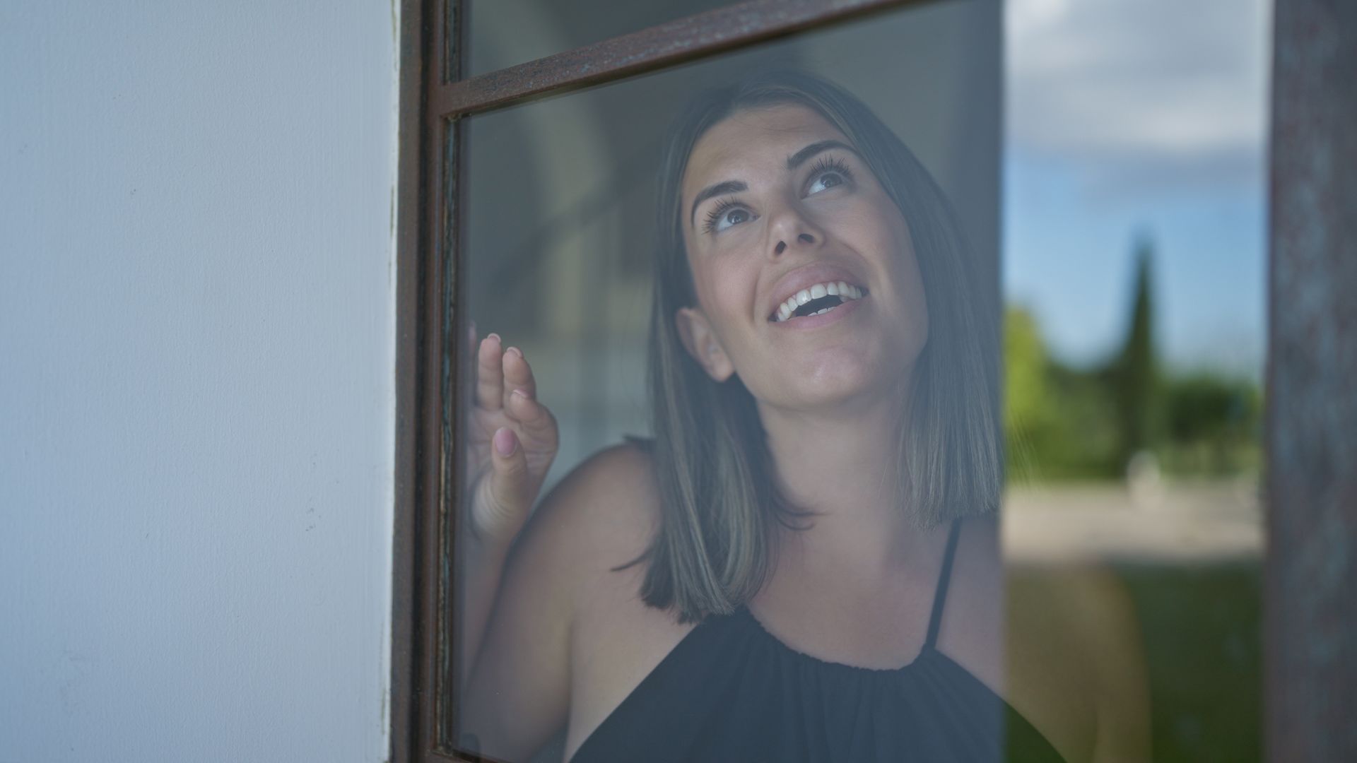 View of a woman looking through a clear glass window. View of a woman looking through a clear glass window.