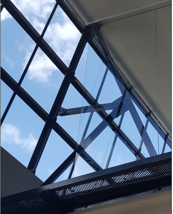 Skylight with black metal framework and blue sky visible through the glass.