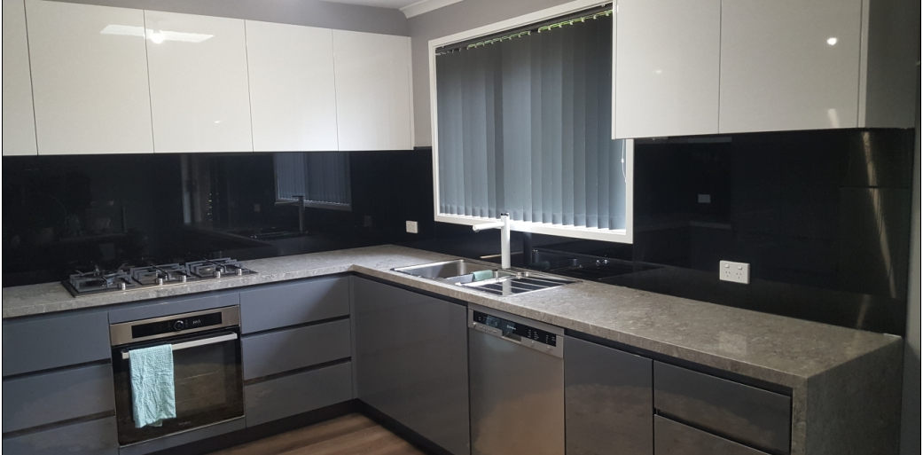 Modern kitchen with gray cabinets, white upper cabinets, and black backsplash.