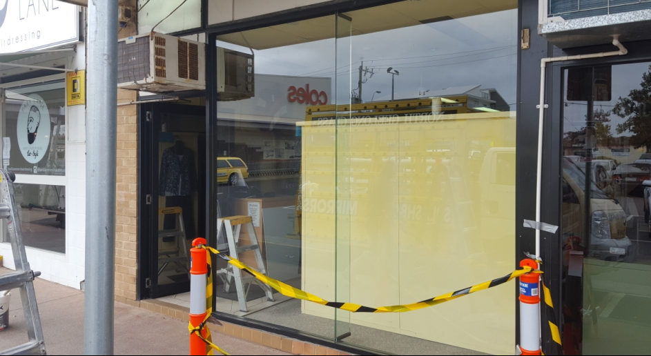 Closed storefront with yellow caution tape. A ladder and AC unit are visible.