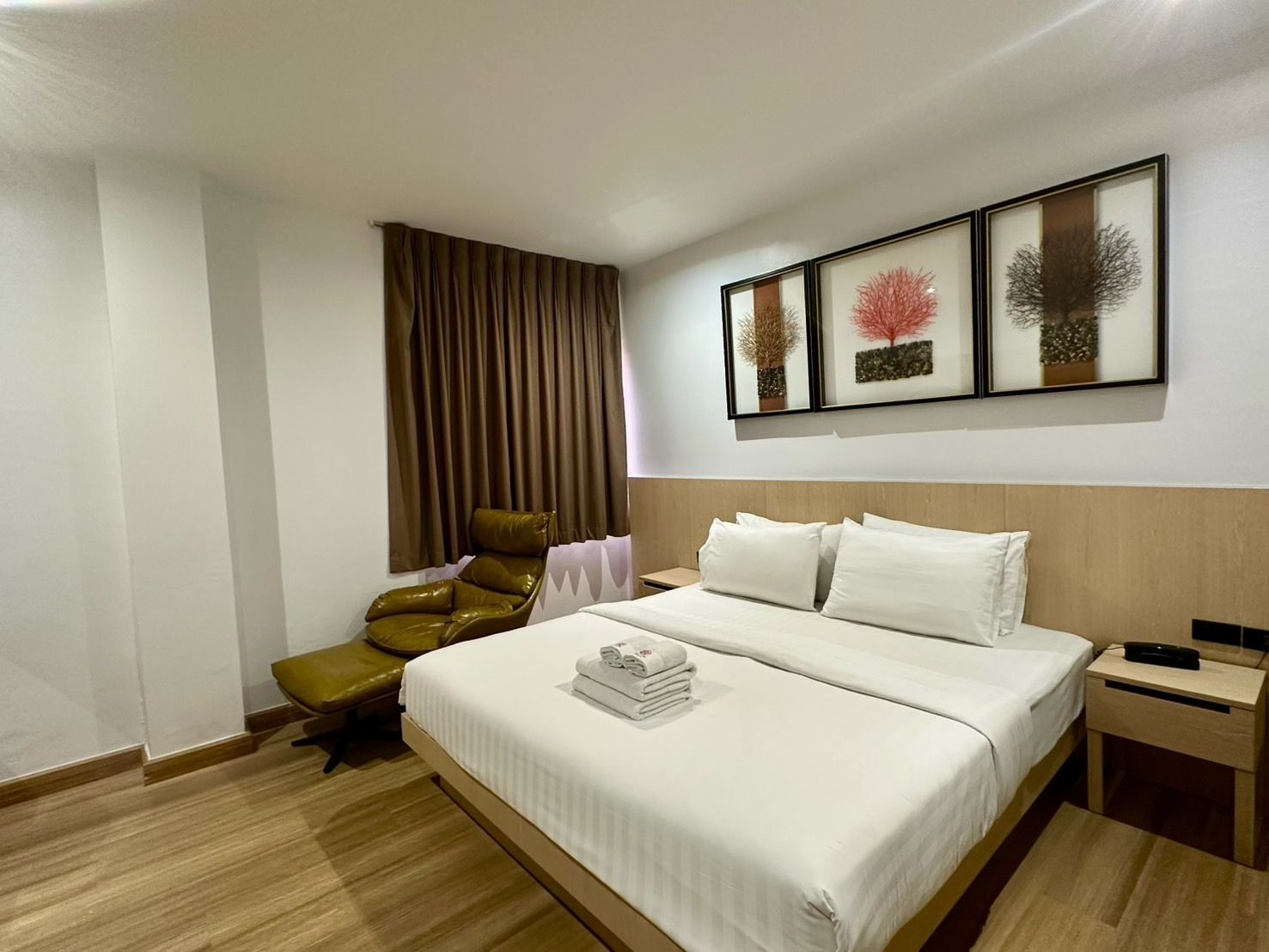 Bedroom with a king bed, chaise lounge, nightstand, and art; brown and white color scheme.