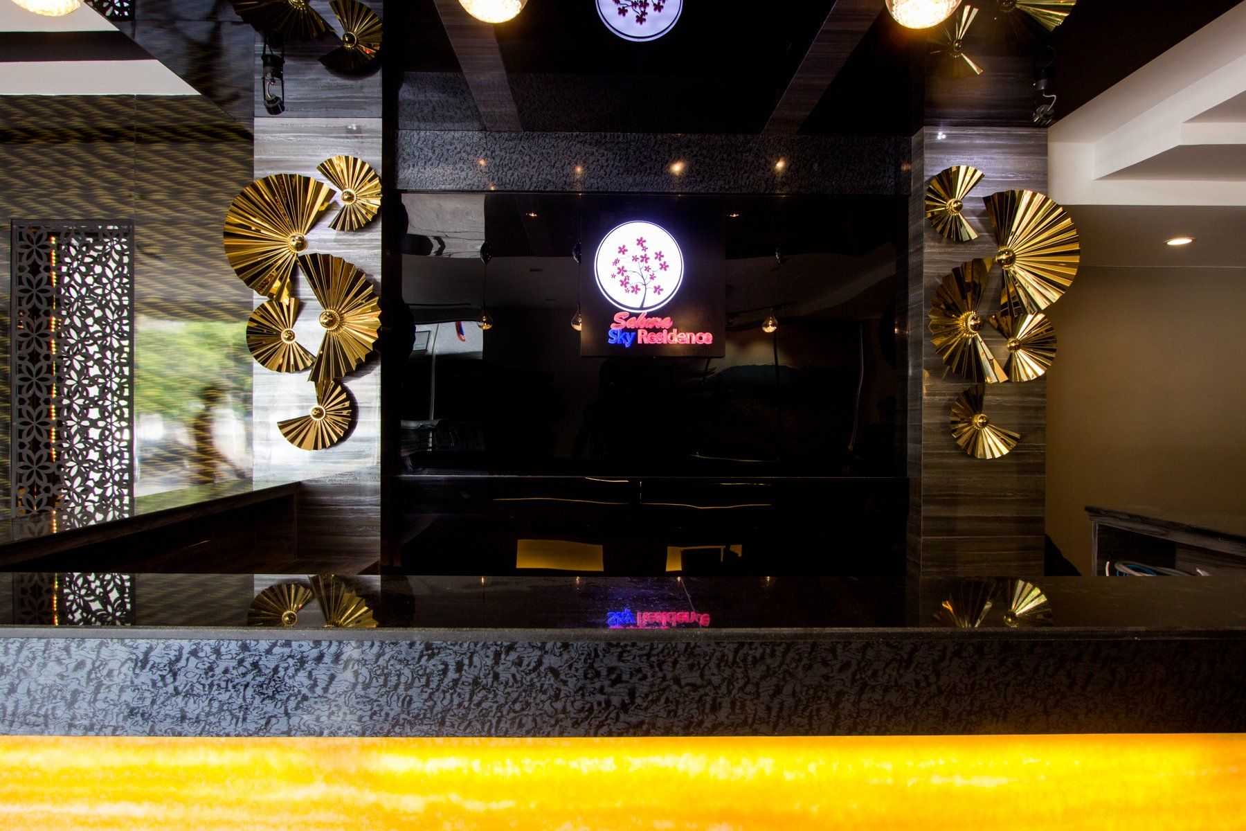 Hotel reception desk with gold art, logo, and dark wall.