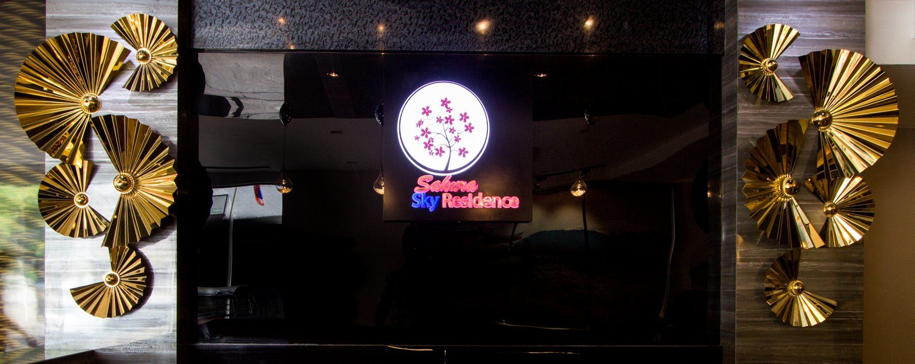 Gold wall decor with restaurant logo on a dark background.