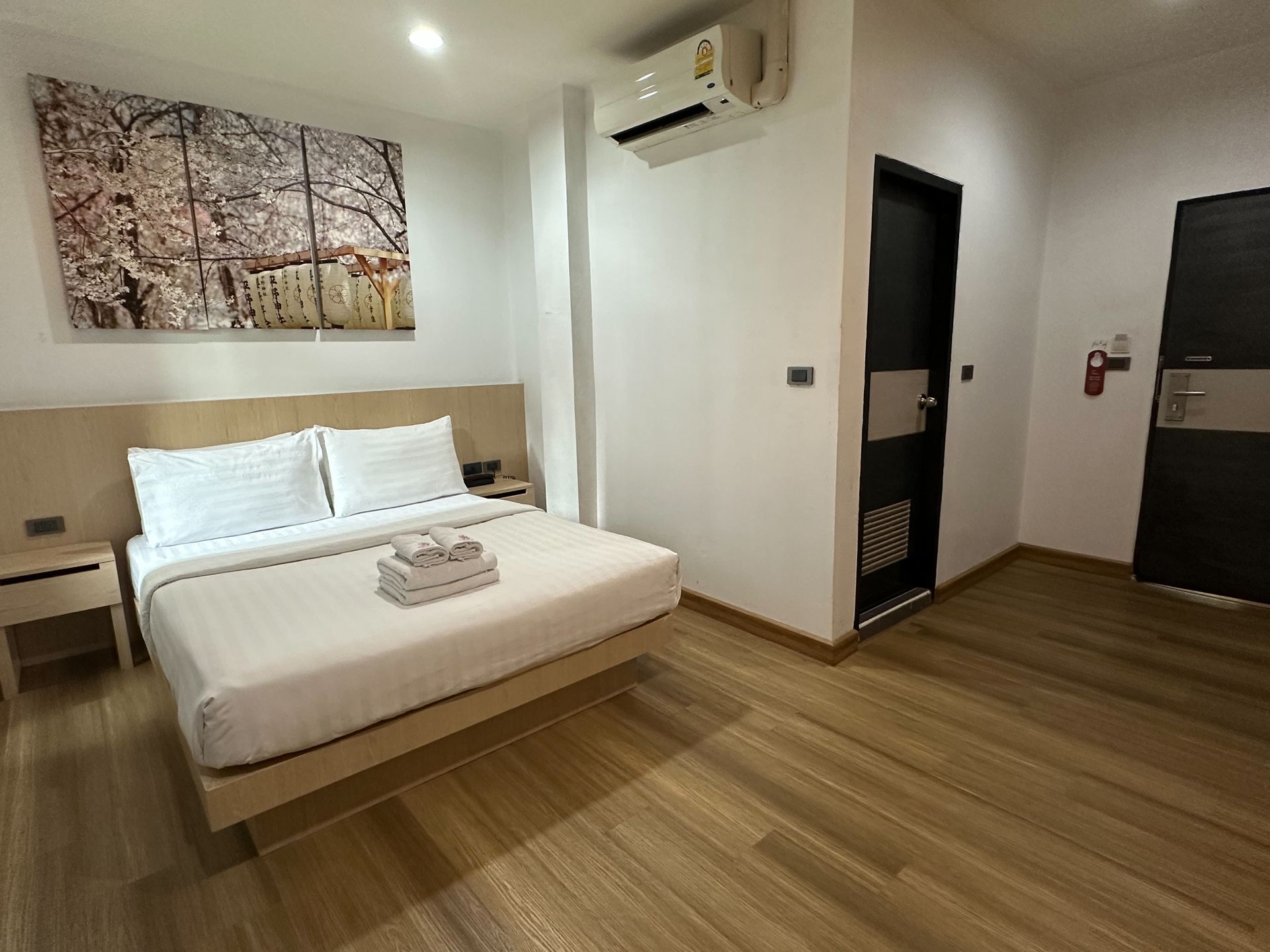 Bedroom with bed, art, air conditioner, and two closed doors.