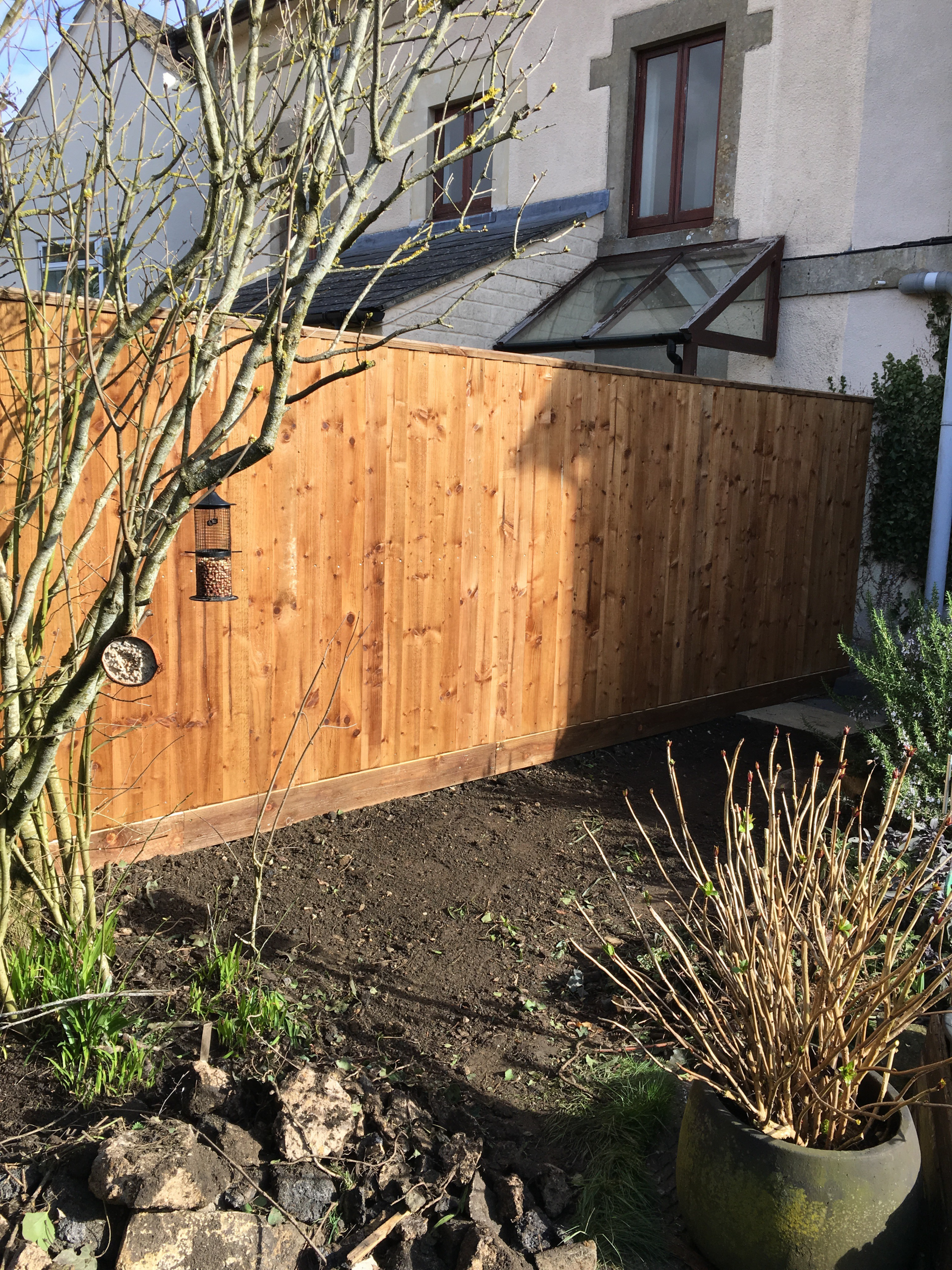 A wooden fence in a garden next to a house.