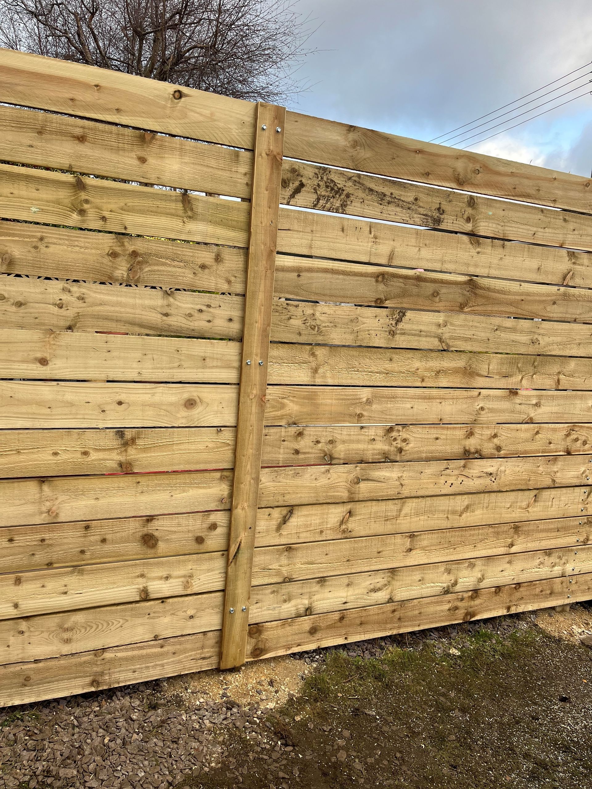 A close up of a wooden fence with a tree in the background.
