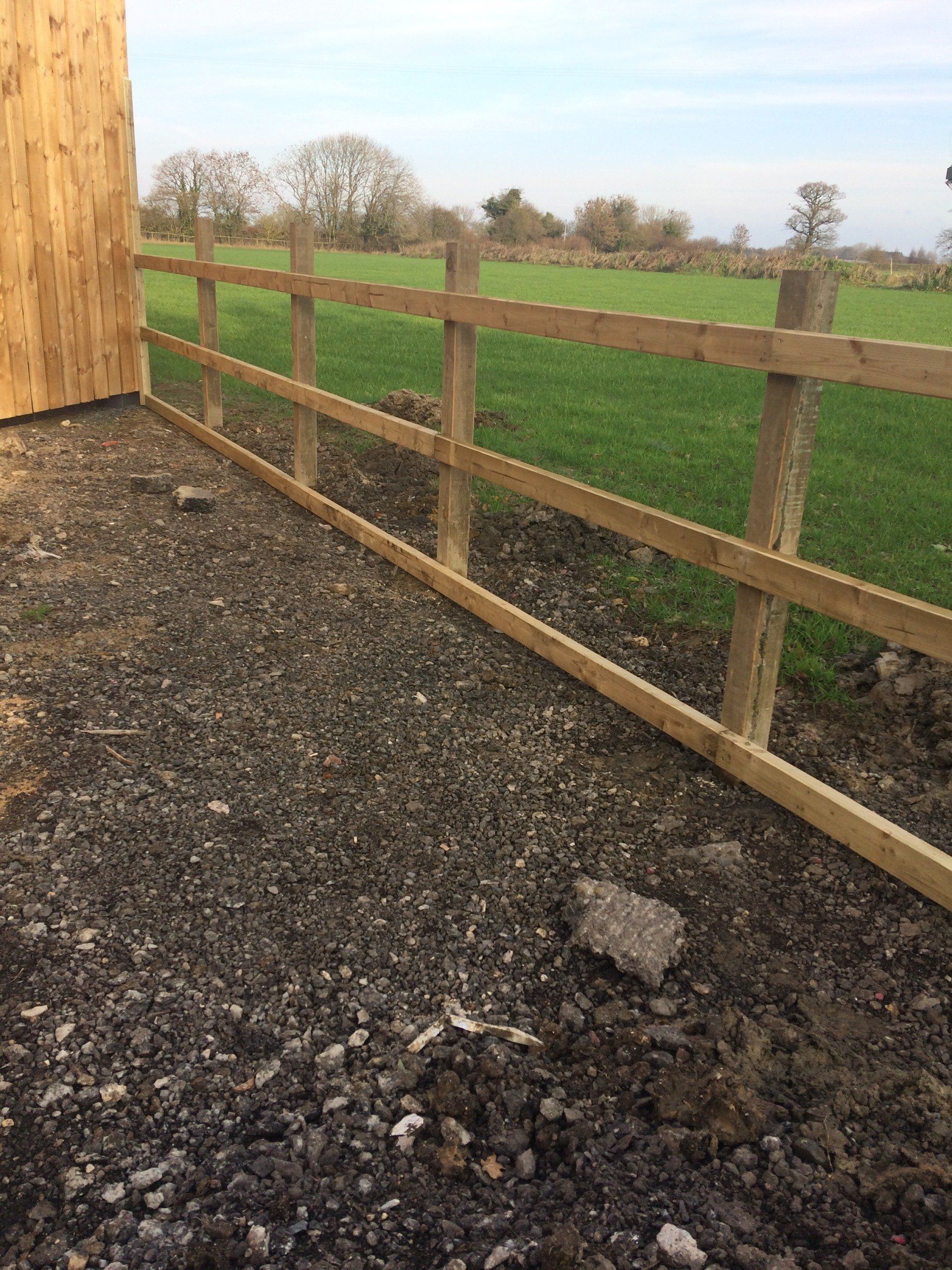 A wooden fence is surrounding a field of grass.