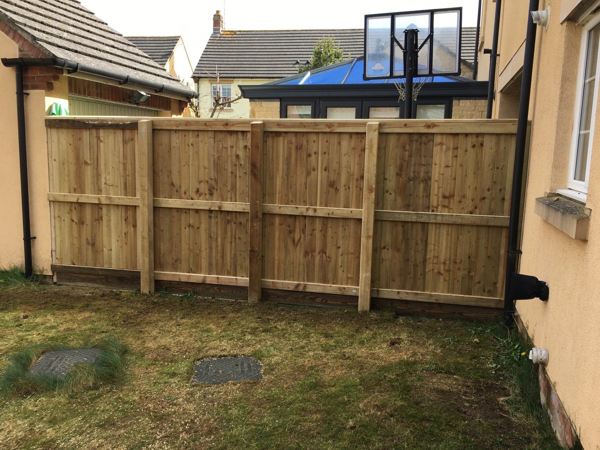 A wooden fence is in the backyard of a house.