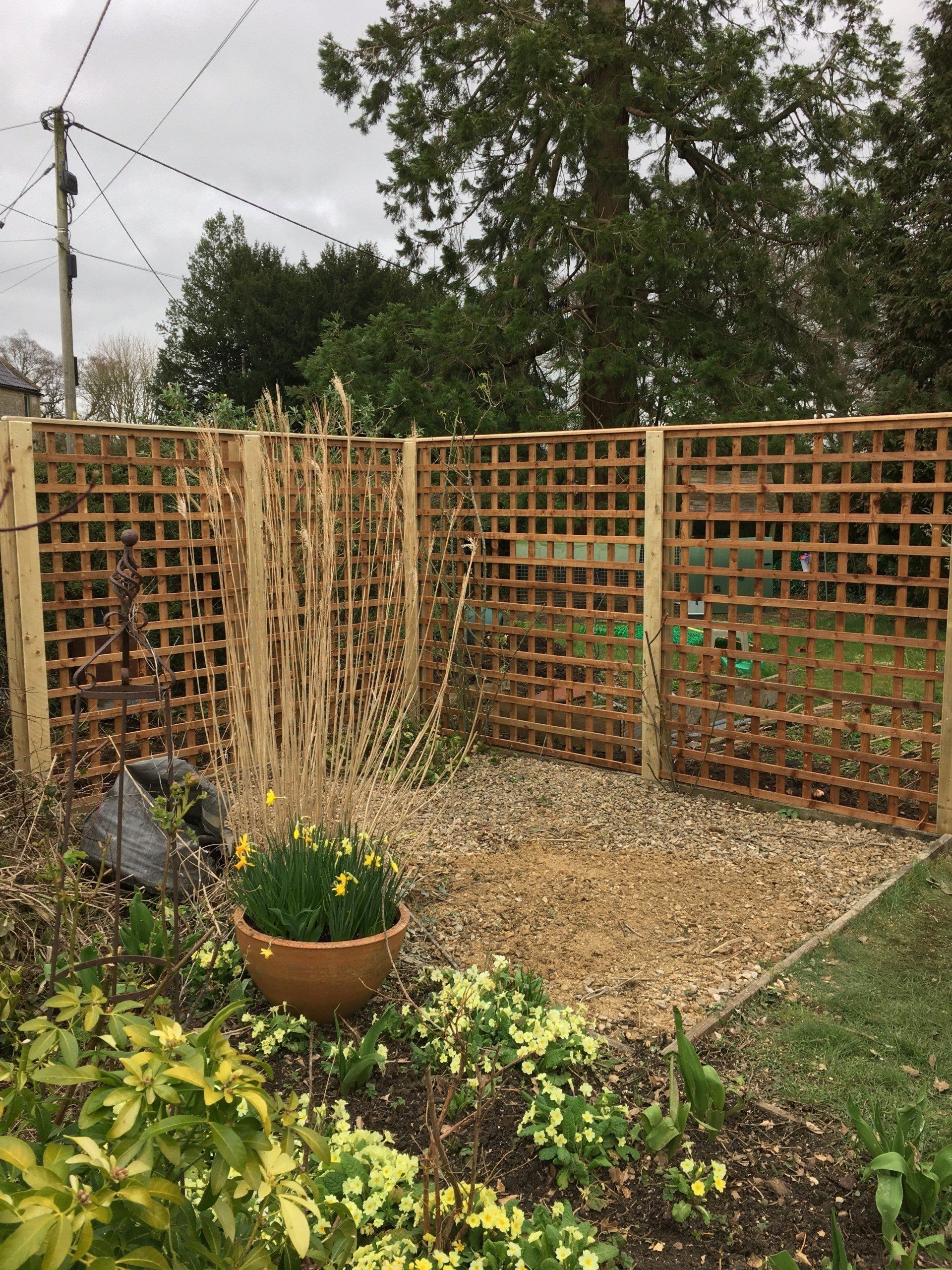 A garden with a wooden fence and a potted plant in the middle.