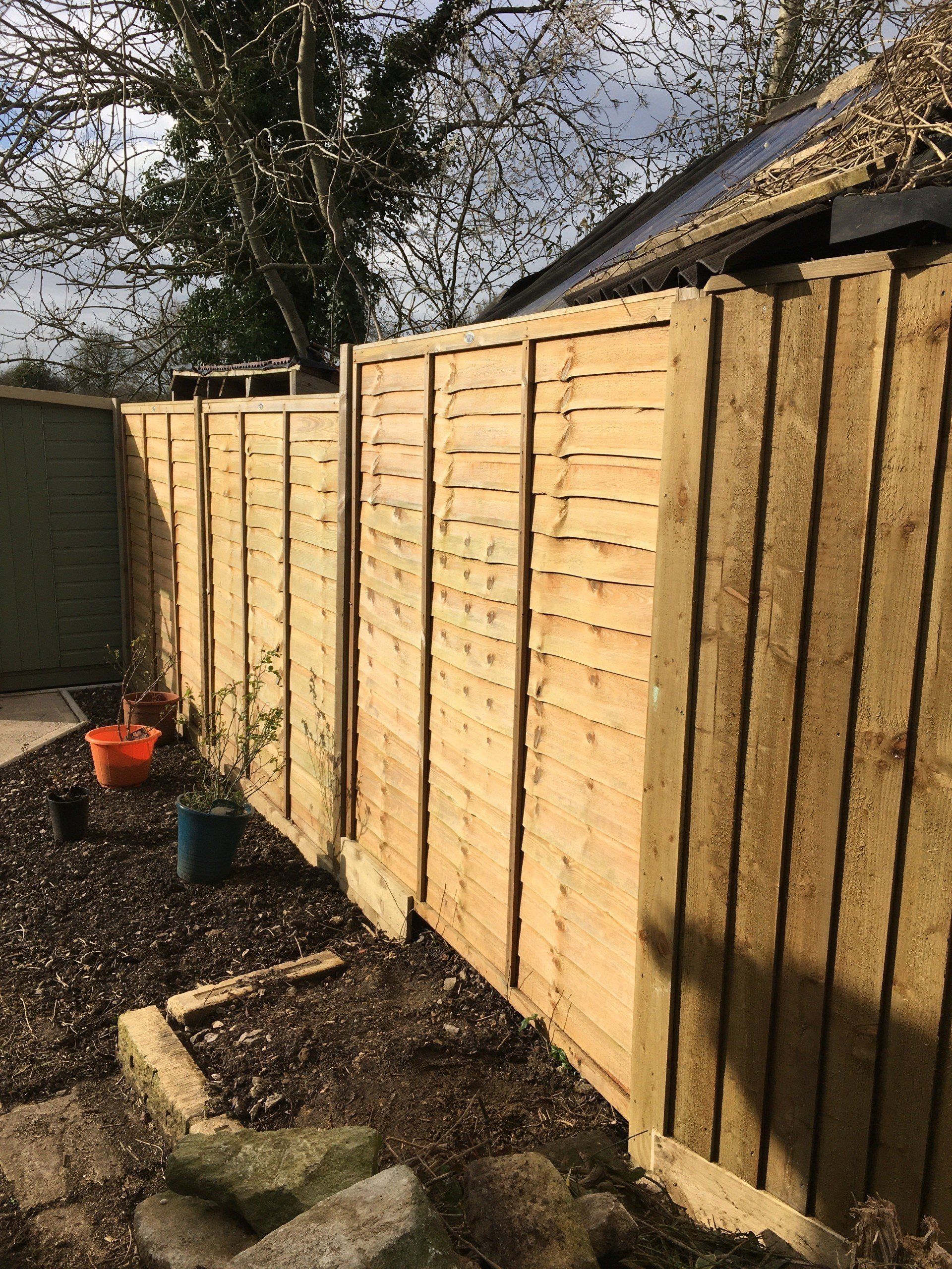 A wooden fence is being built in a backyard.