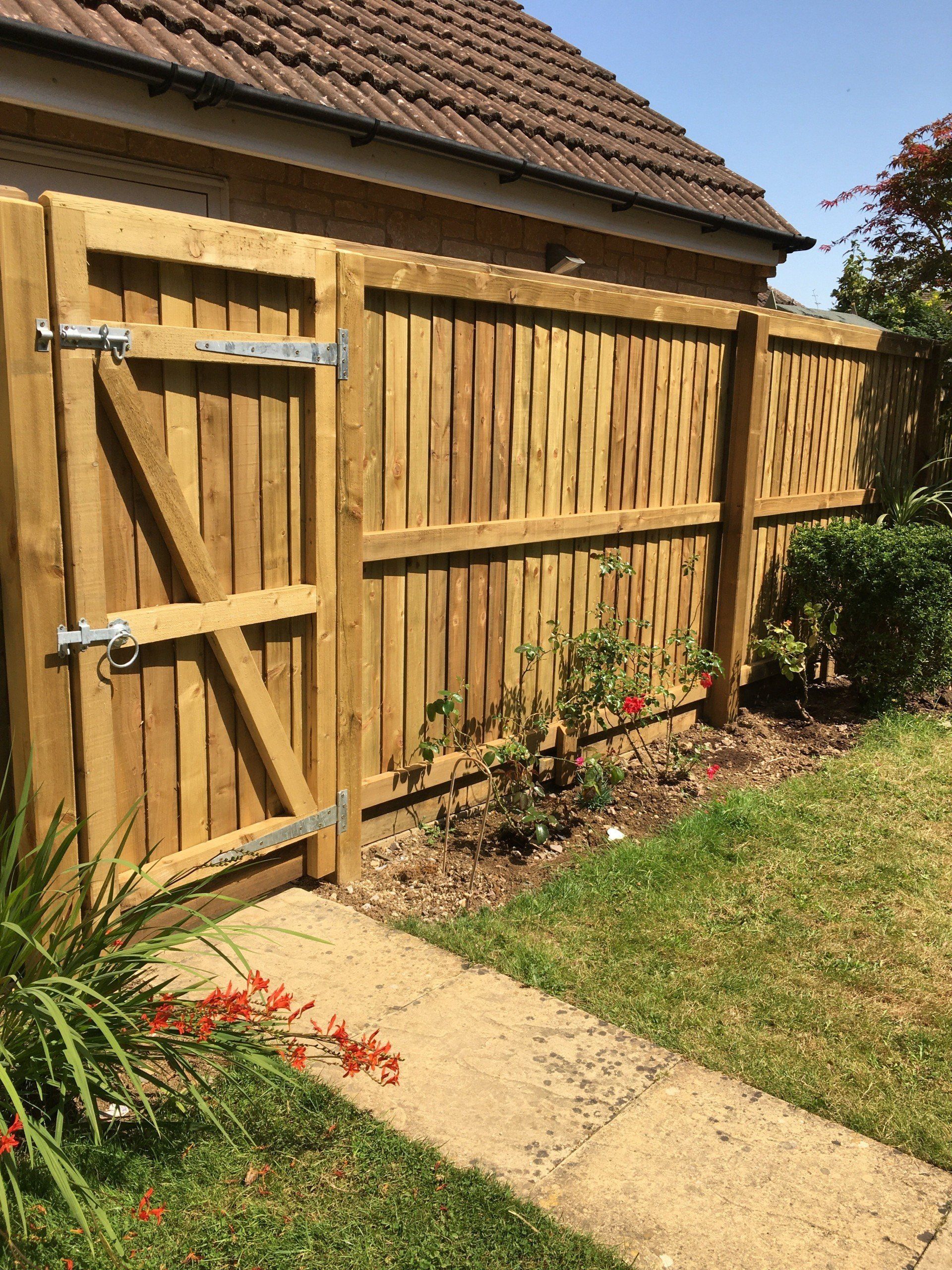 A wooden fence with a gate in front of a house.