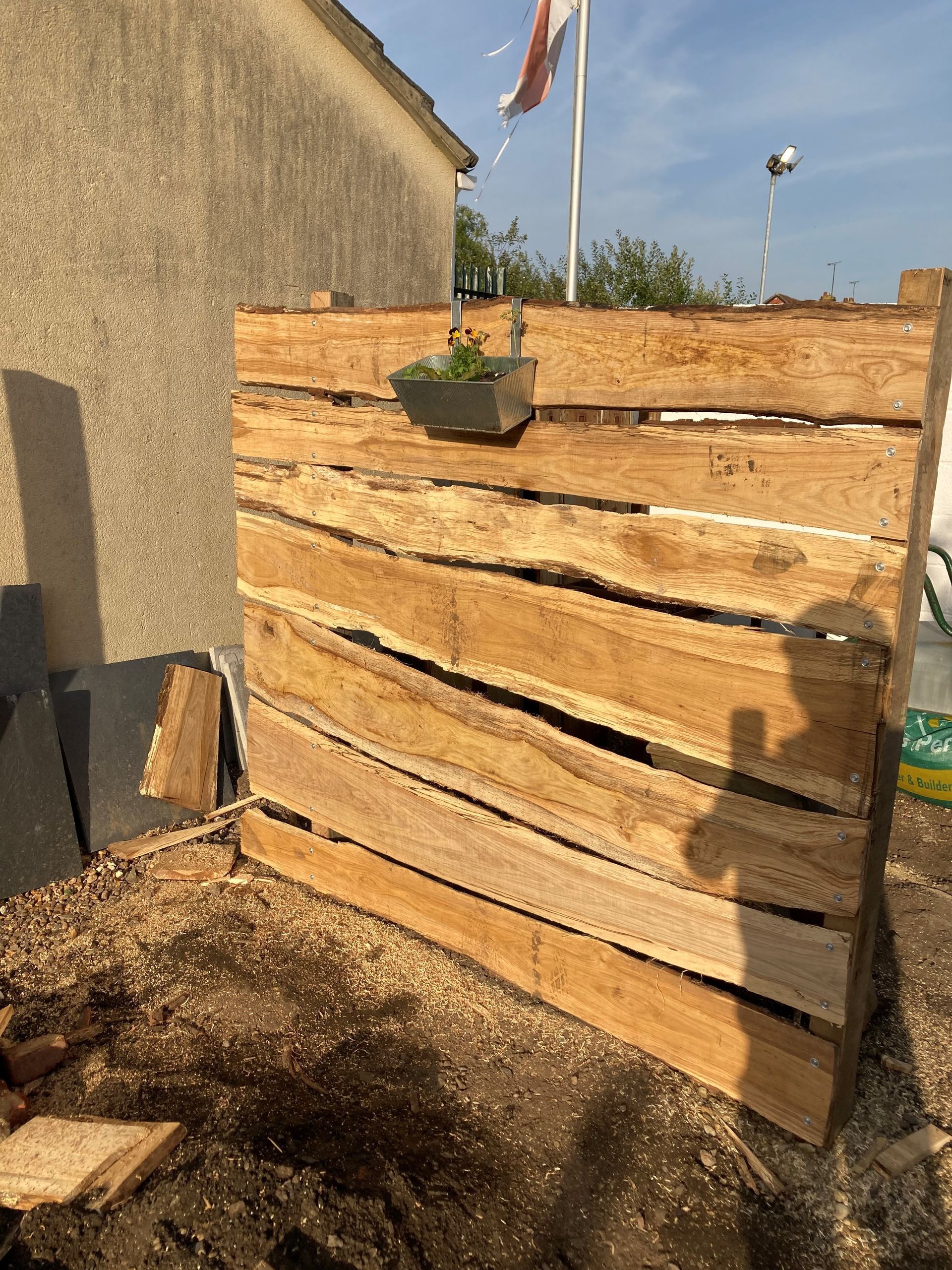 A wooden fence with a potted plant hanging from it.
