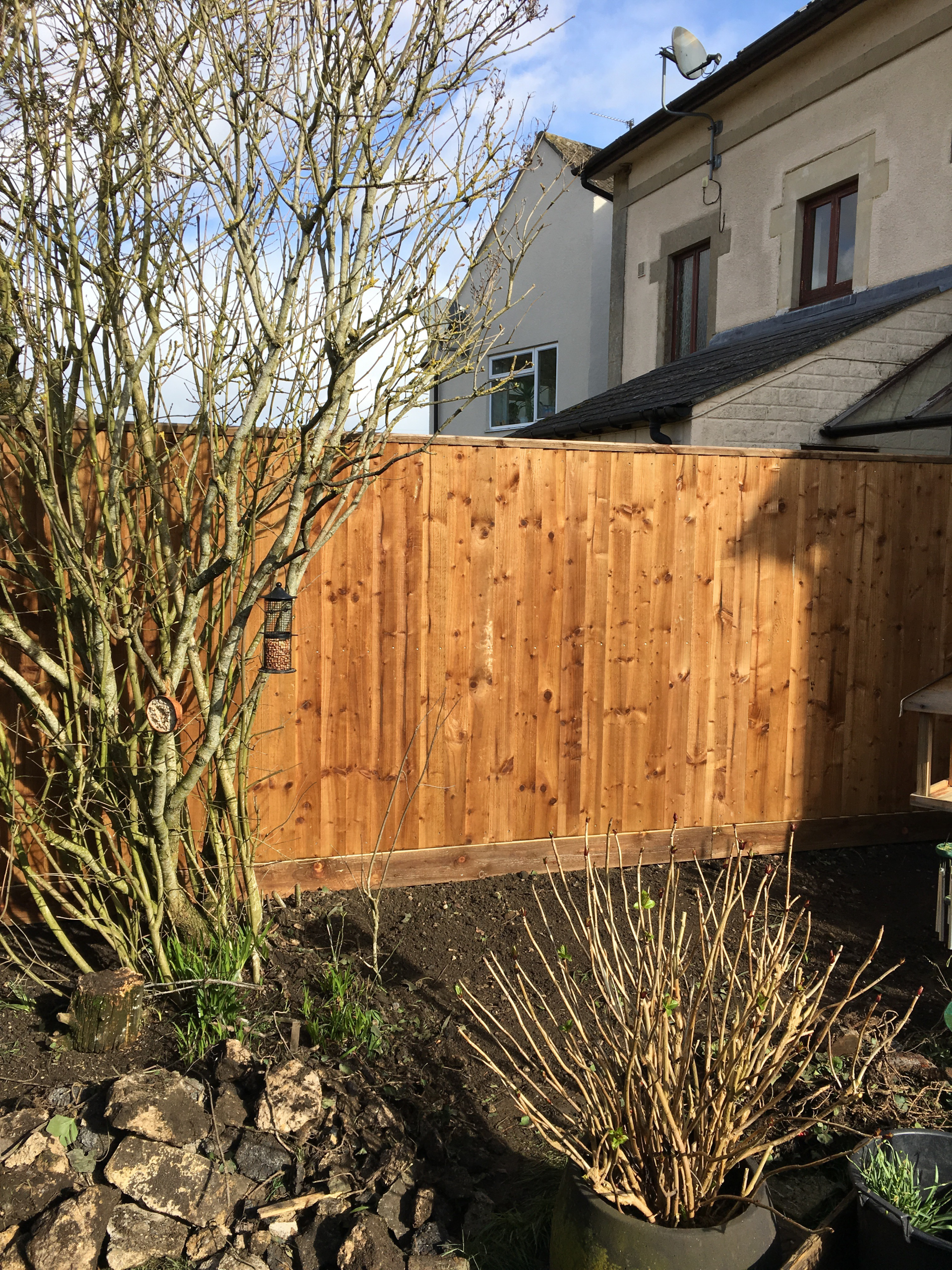 A wooden fence is in the backyard of a house.