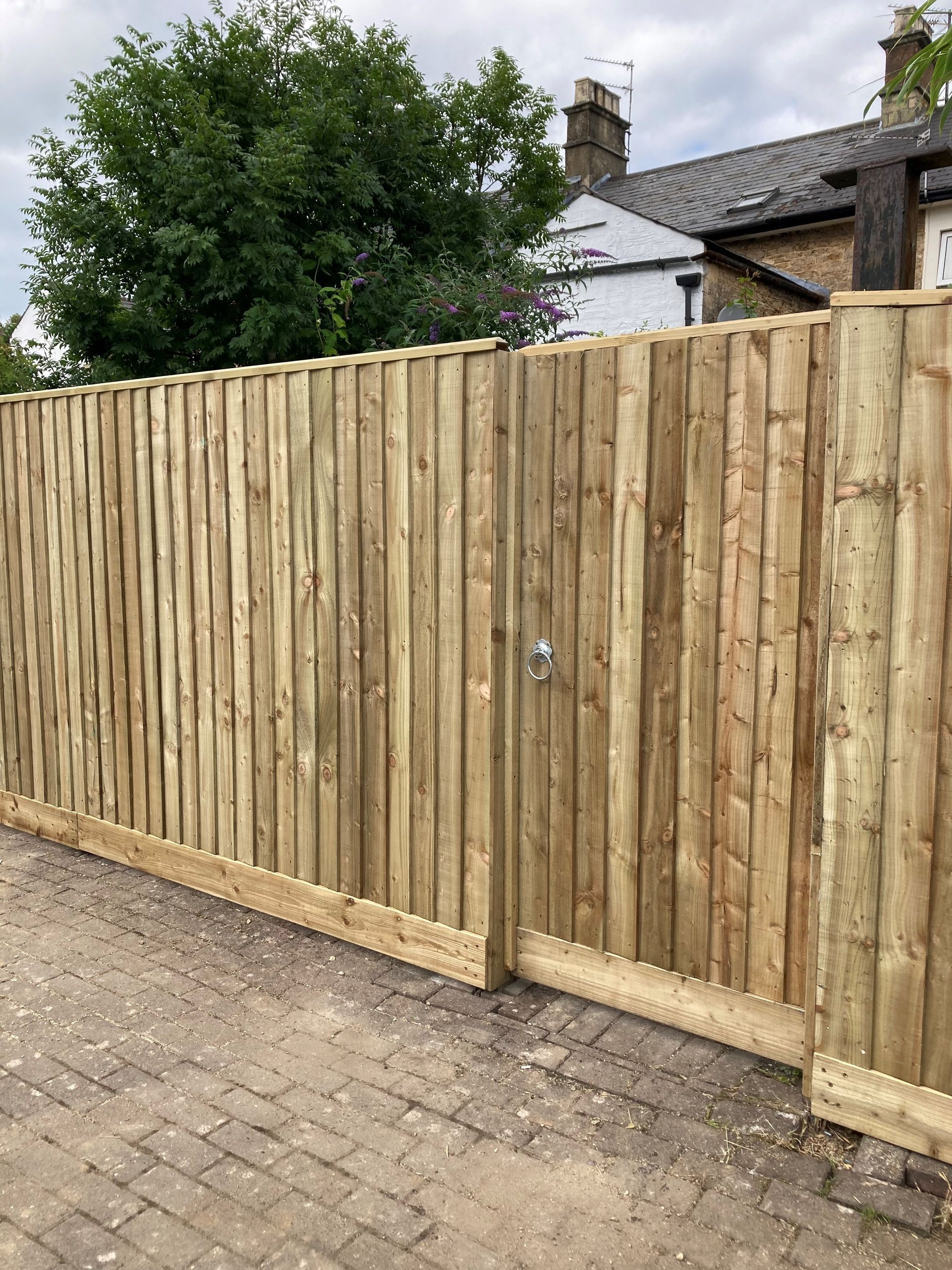A wooden fence with a gate in front of a house.