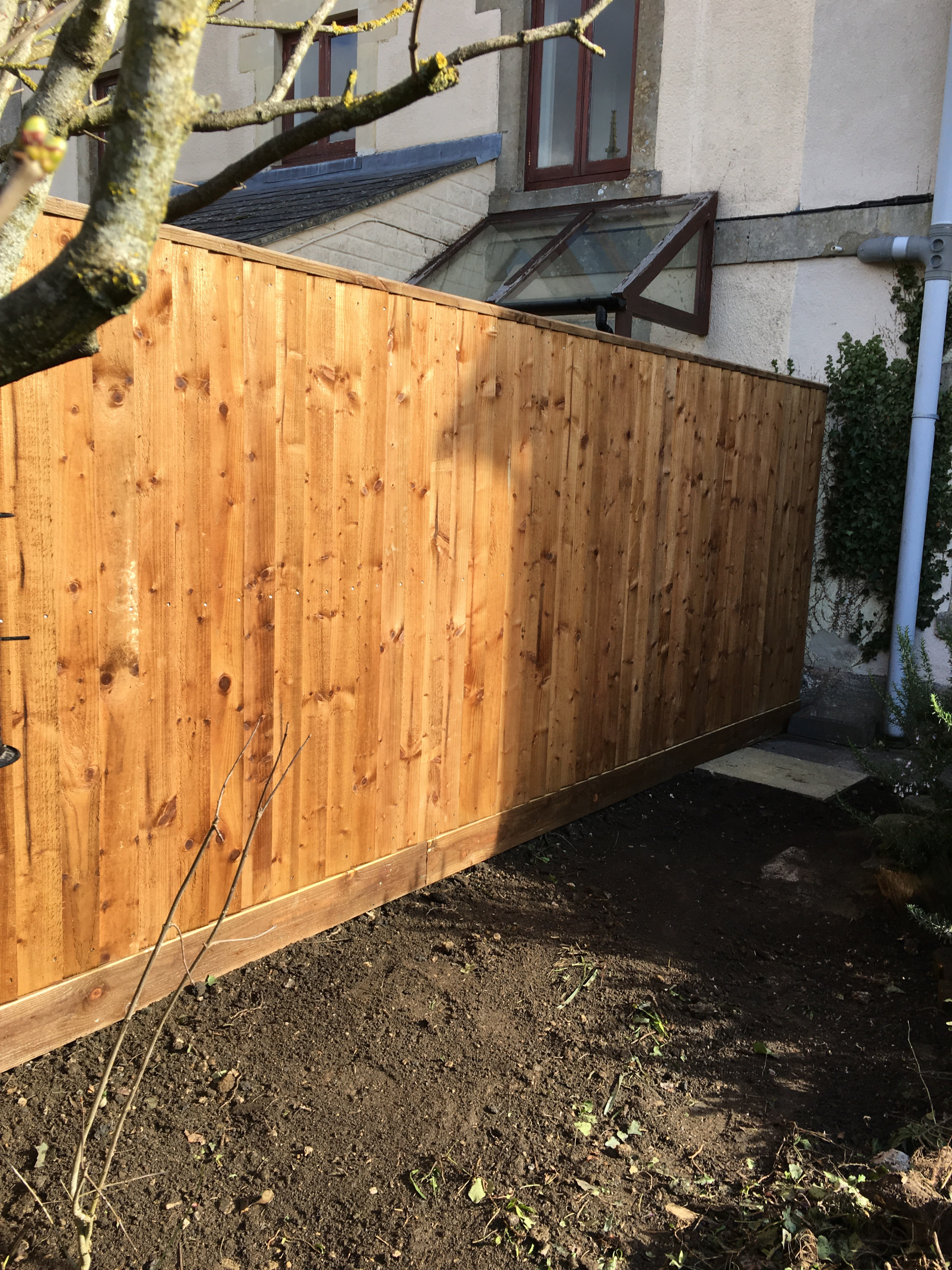 A wooden fence is in the backyard of a house.