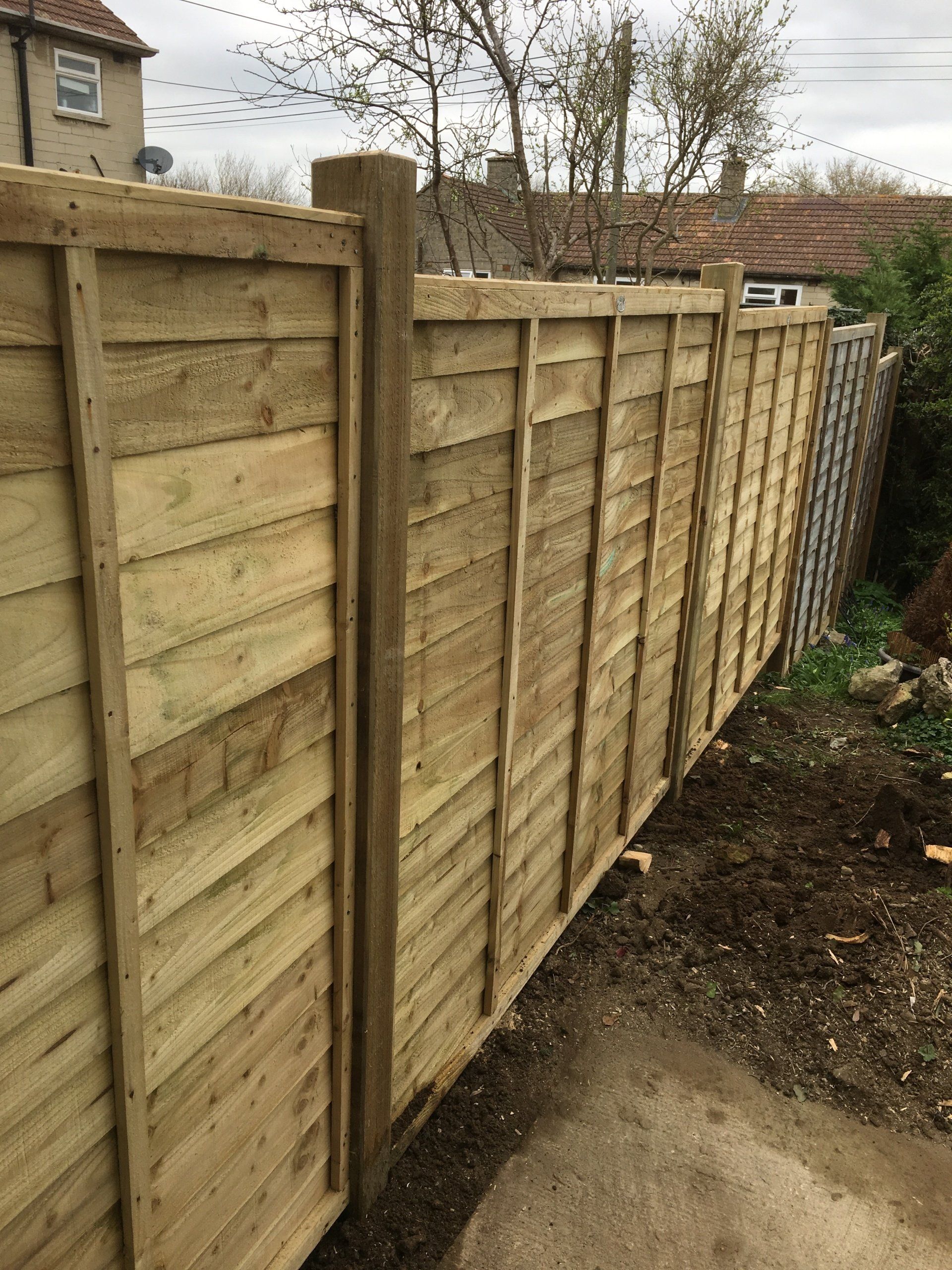 A wooden fence is being built in a backyard.