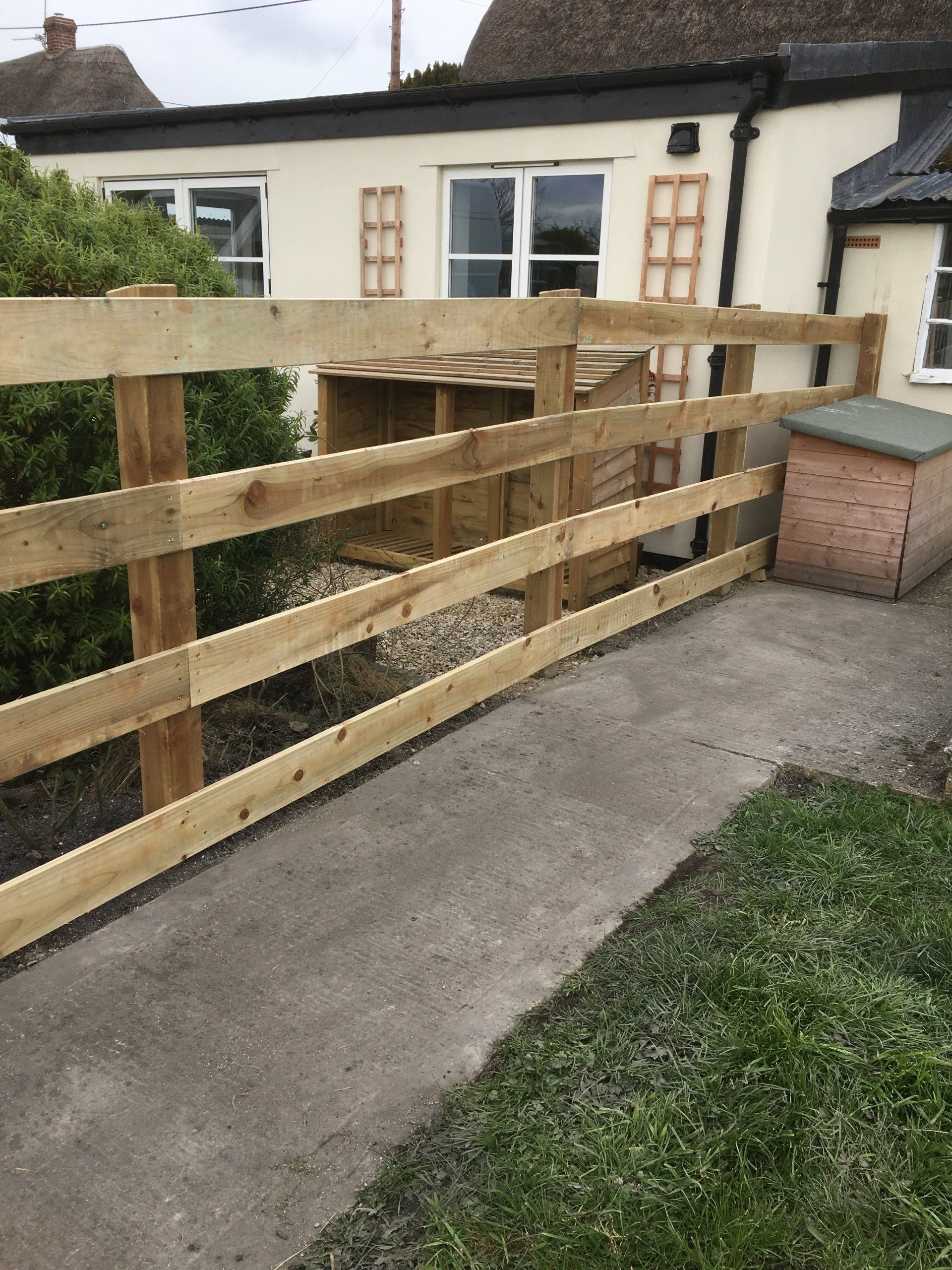 A wooden fence is sitting on the sidewalk in front of a house.