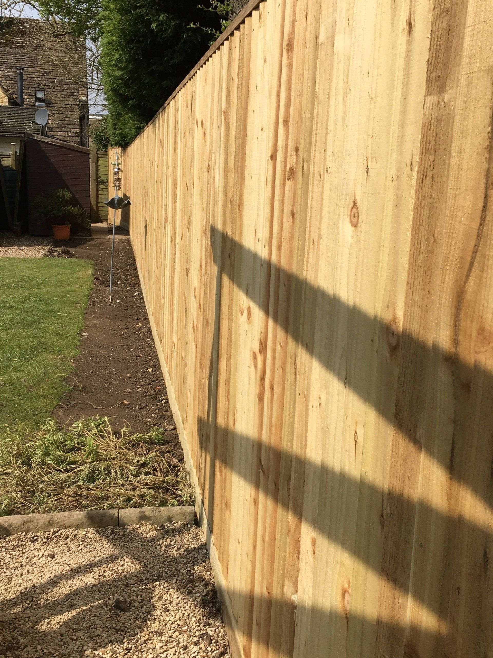 A wooden fence with a shadow on the ground