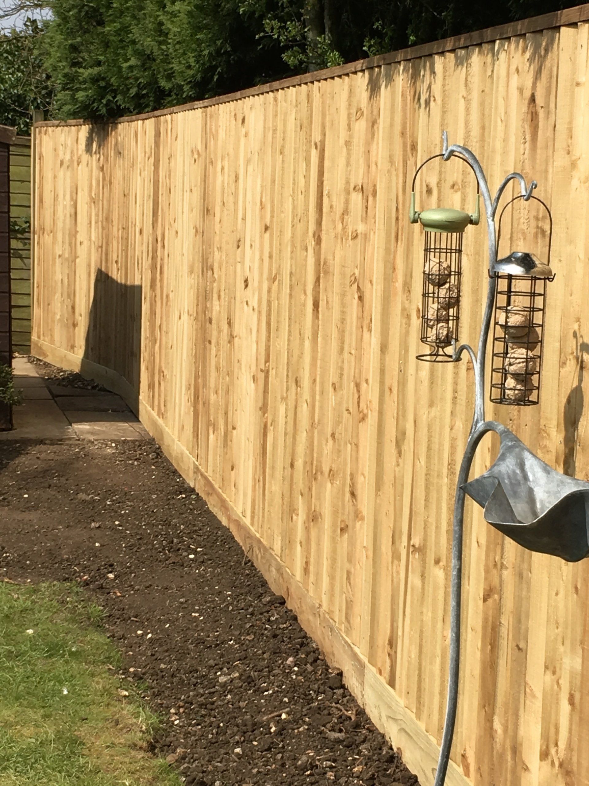 A wooden fence with a bird feeder attached to it.