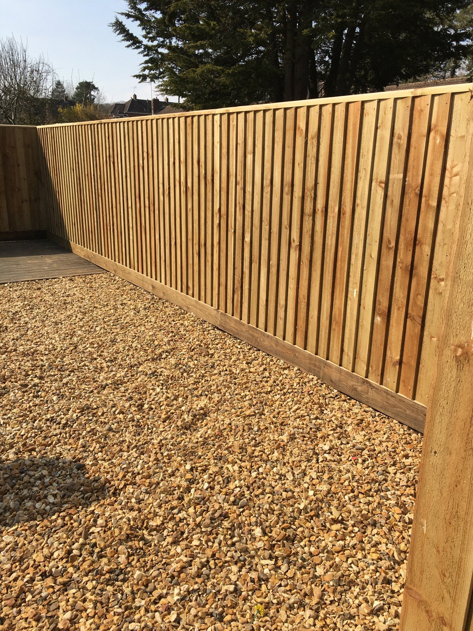 A wooden fence is surrounded by gravel in a yard.