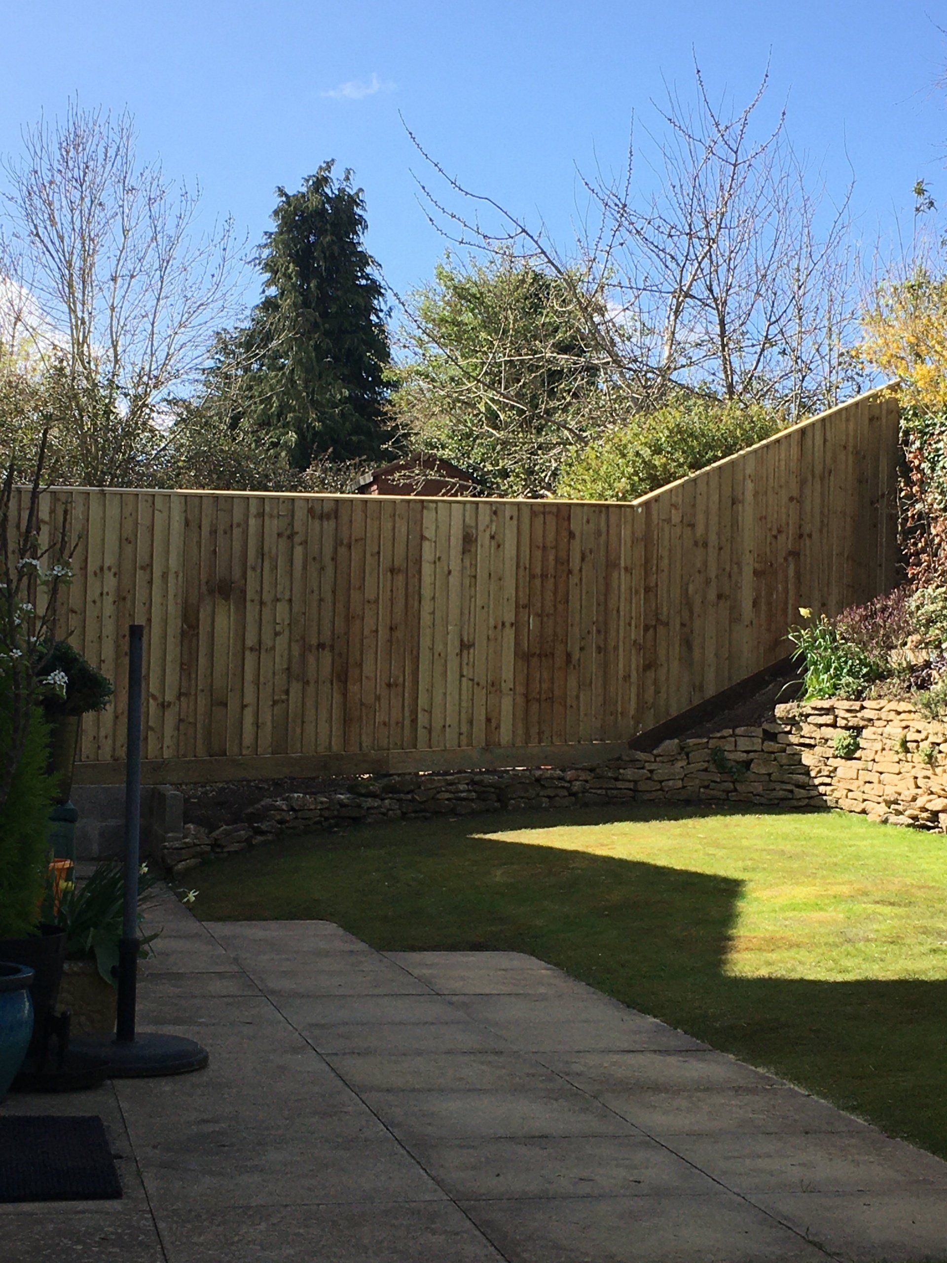 A wooden fence surrounds a lush green lawn in a backyard.