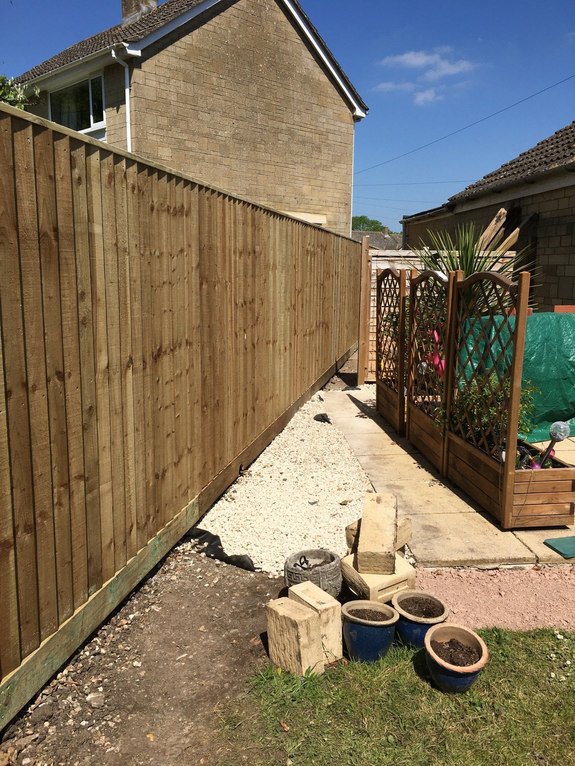 A wooden fence is being built in a backyard next to a house.
