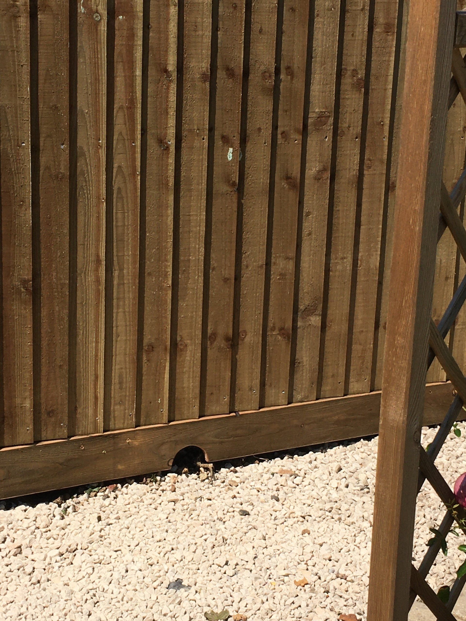 A wooden fence is sitting on top of a pile of gravel.
