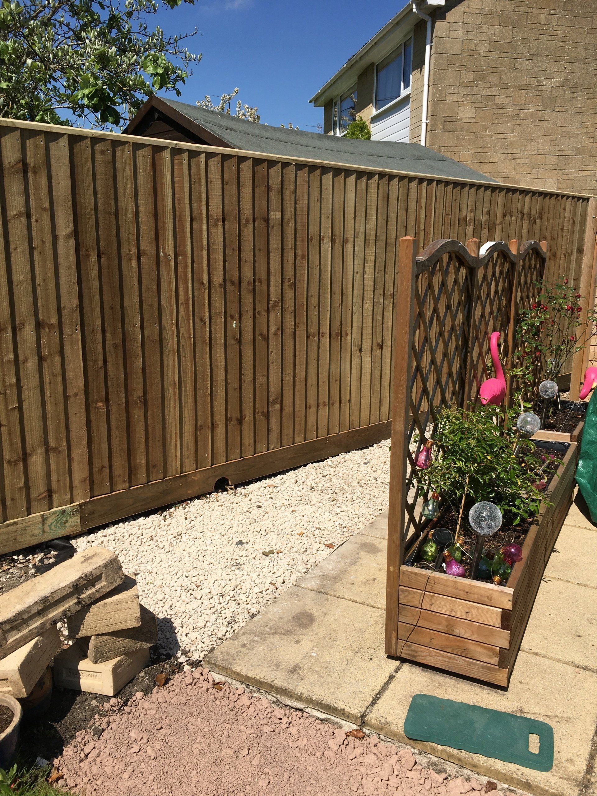 A wooden fence with a planter in front of it.