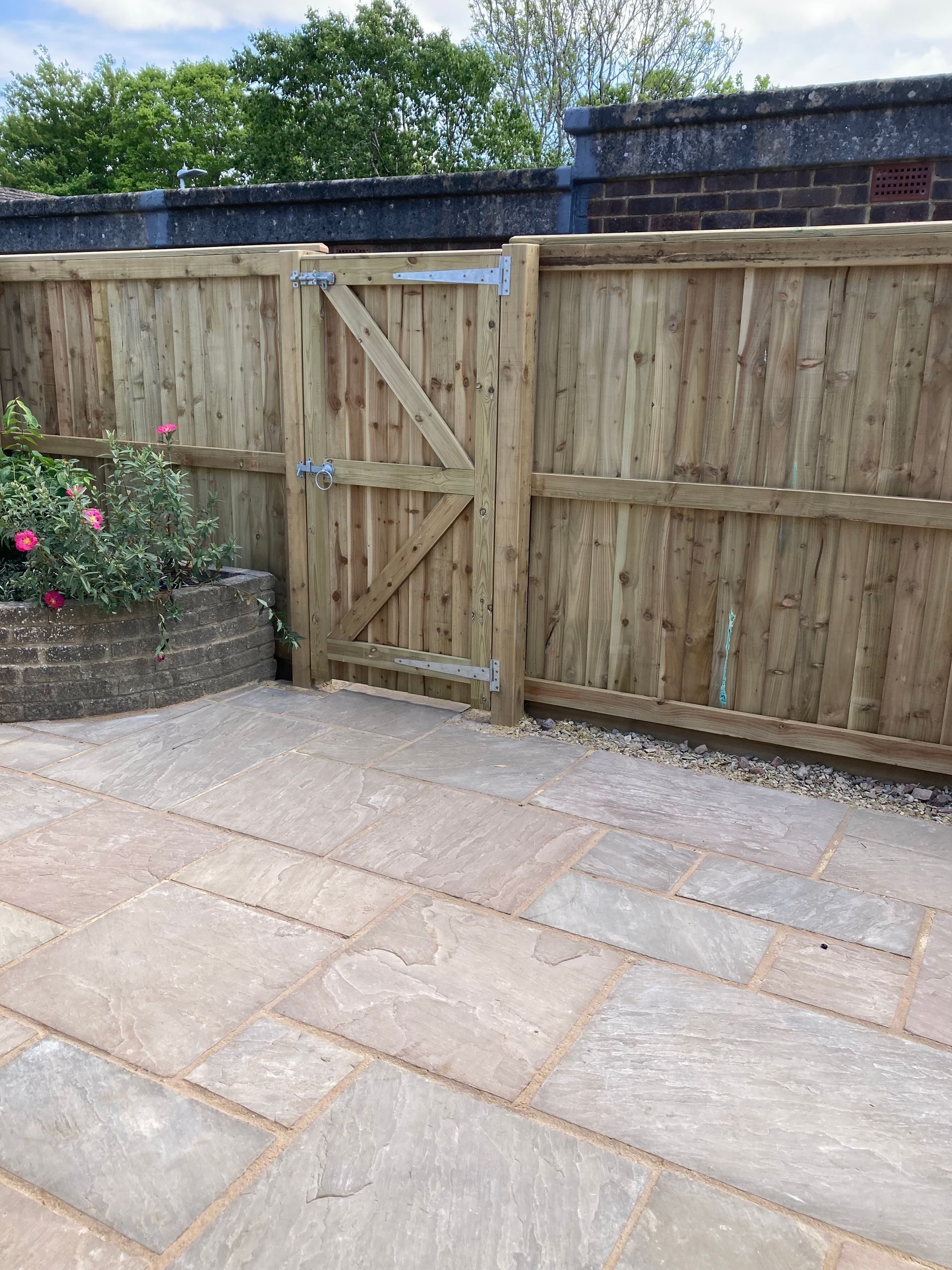 A wooden fence with a gate in the middle of a patio.