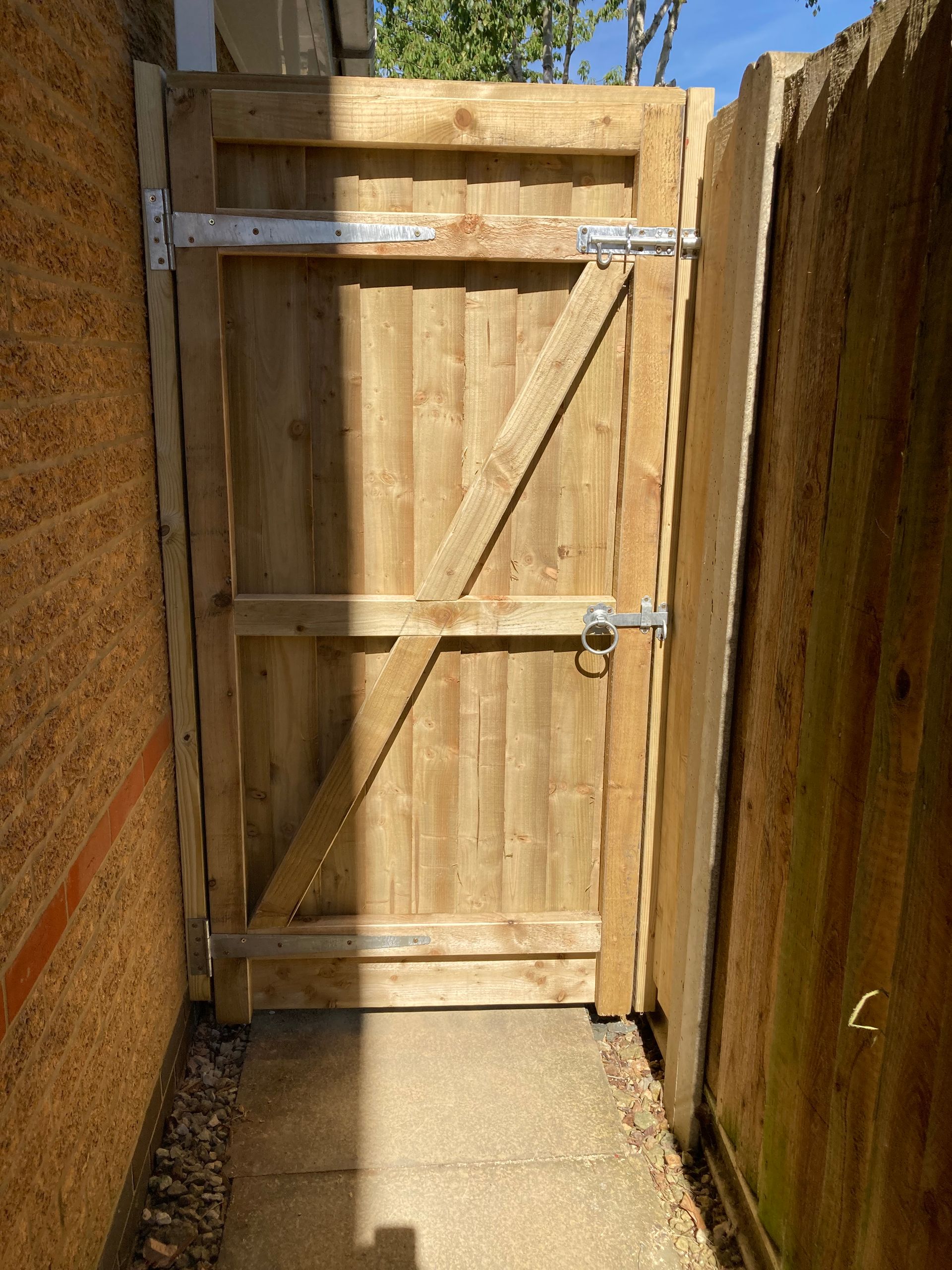 A wooden gate is sitting next to a brick wall.