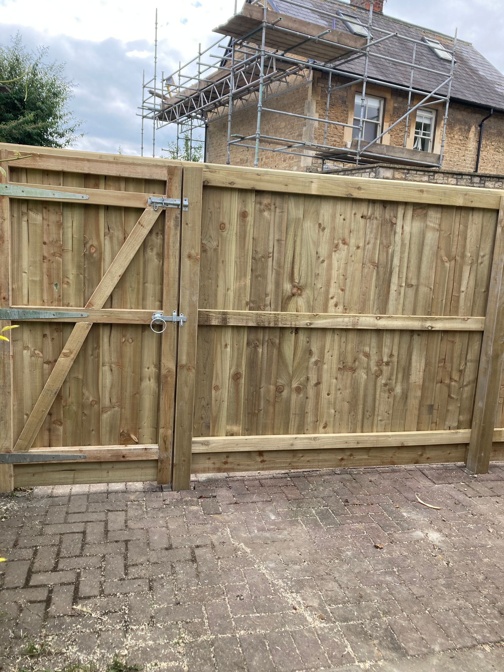 A wooden fence with a gate in front of a house under construction.