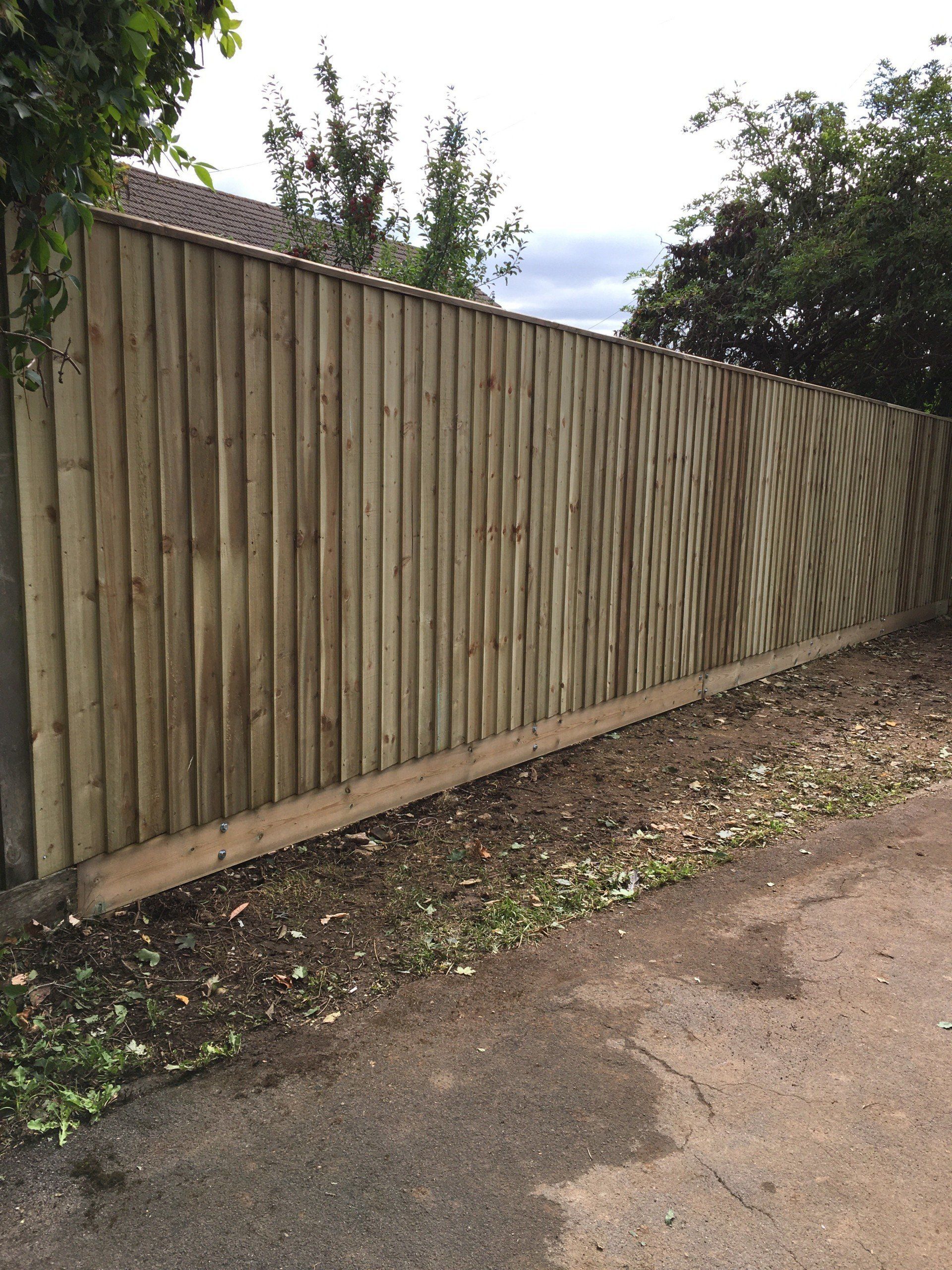 A wooden fence is sitting on the side of a road.