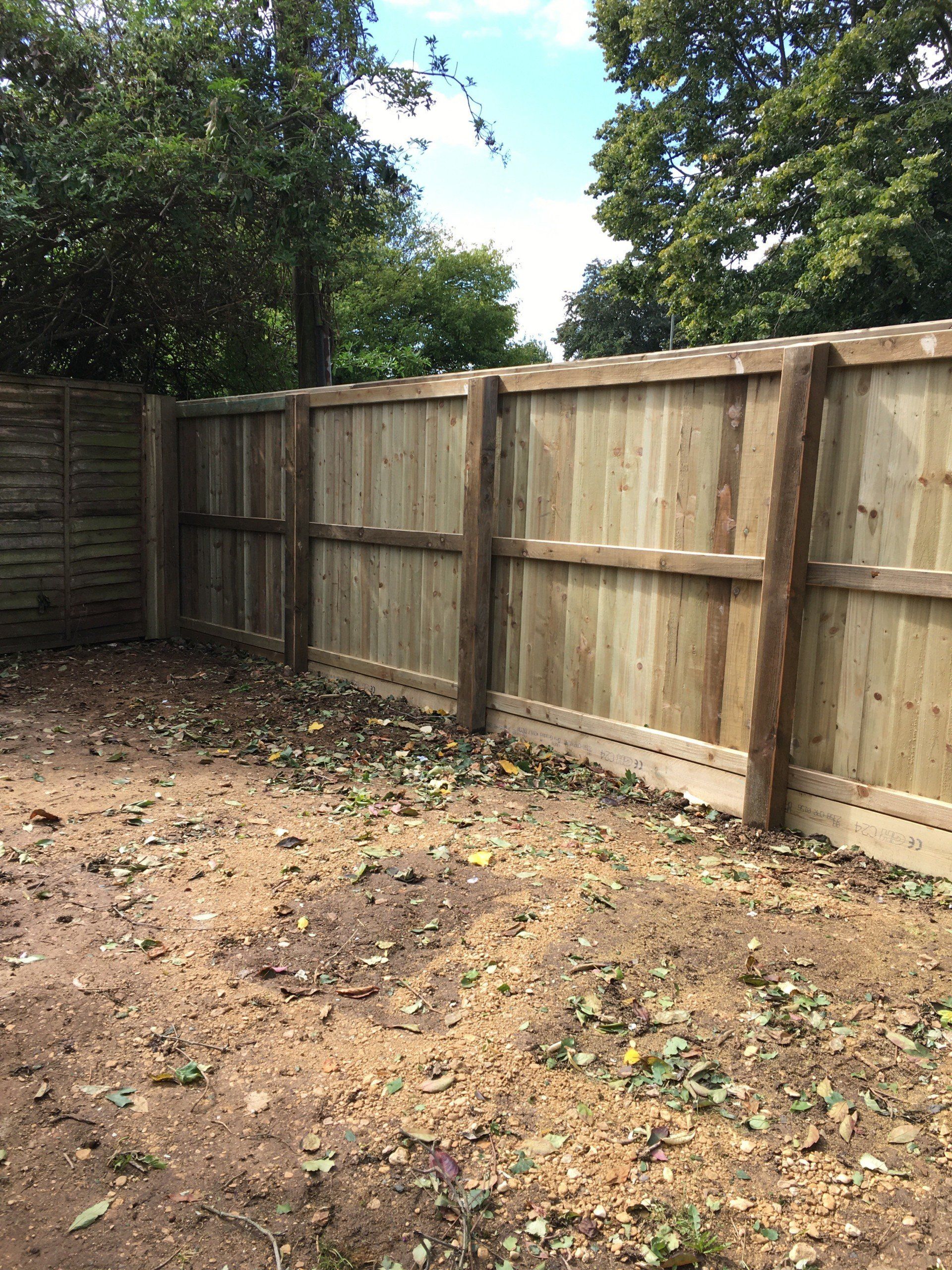 A wooden fence is in the middle of a dirt field.