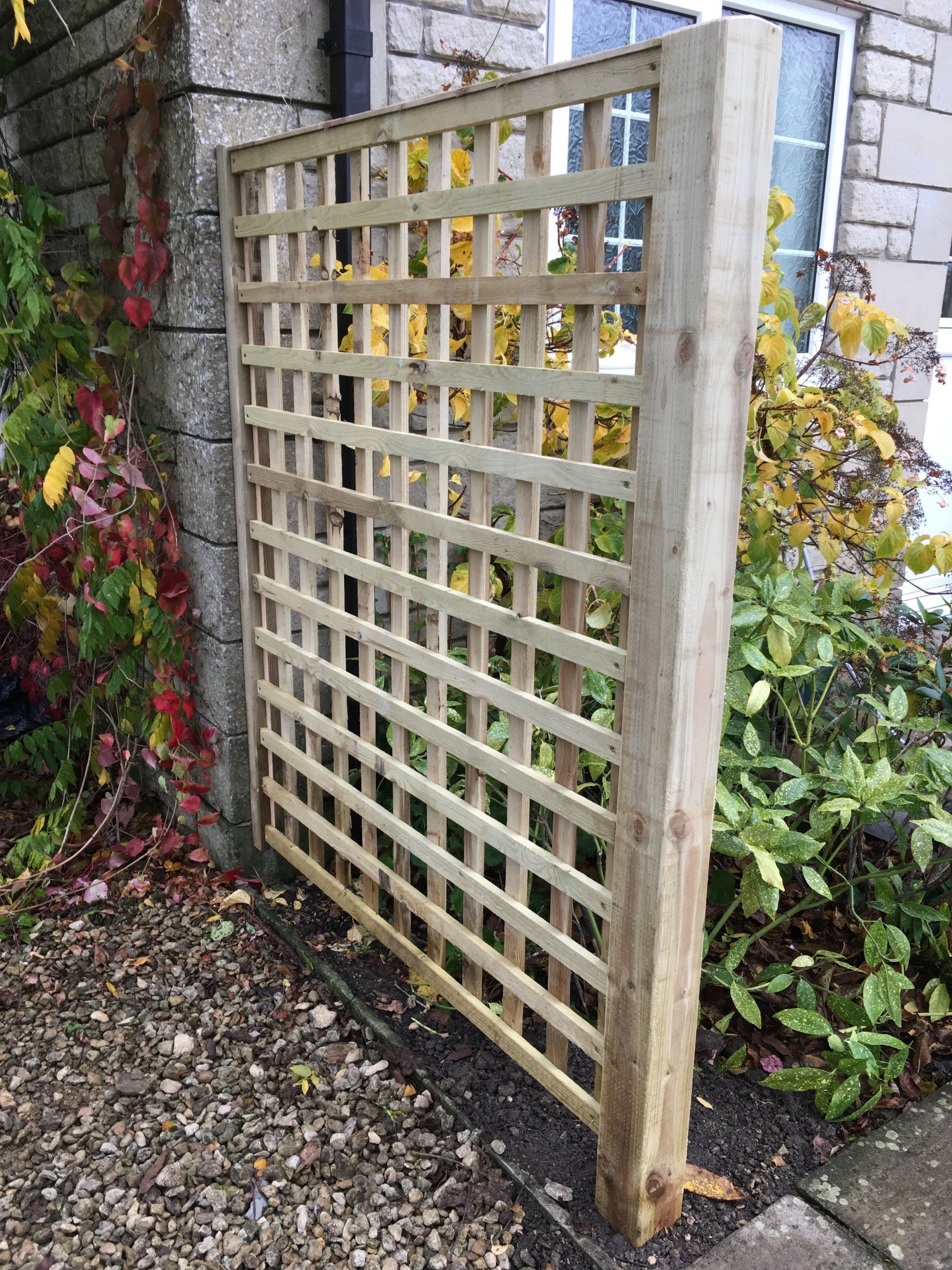 A wooden trellis is sitting next to a brick wall.