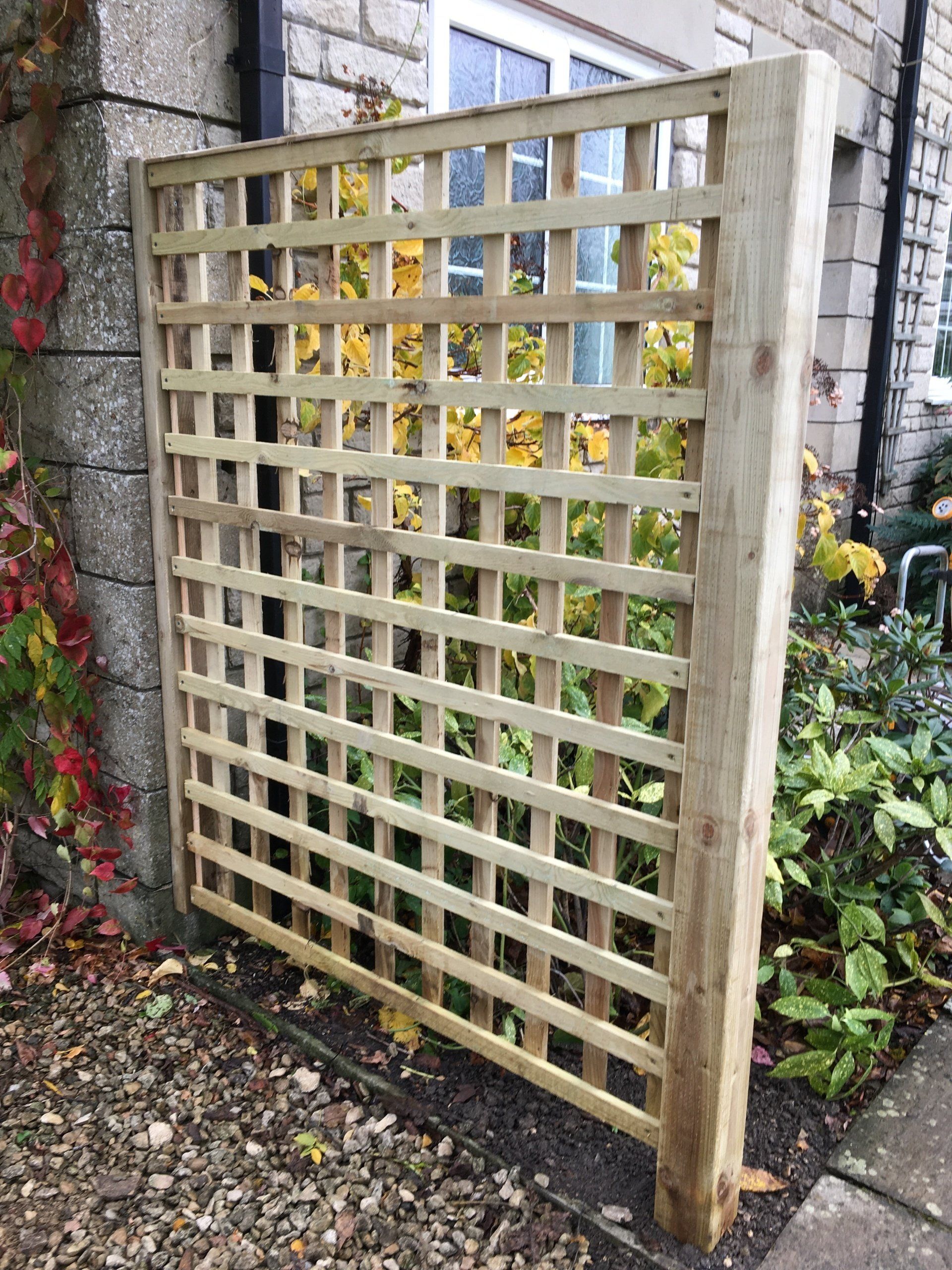 A wooden trellis is sitting next to a brick wall.