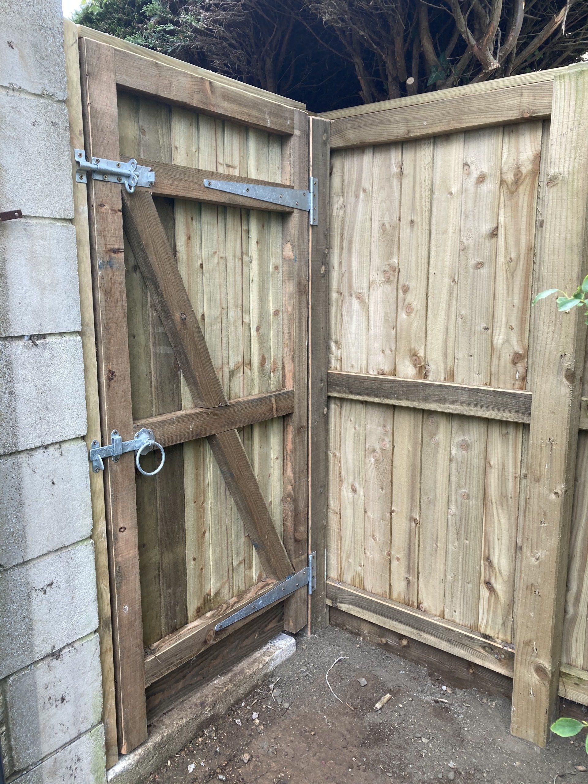A wooden gate is sitting next to a wooden fence.