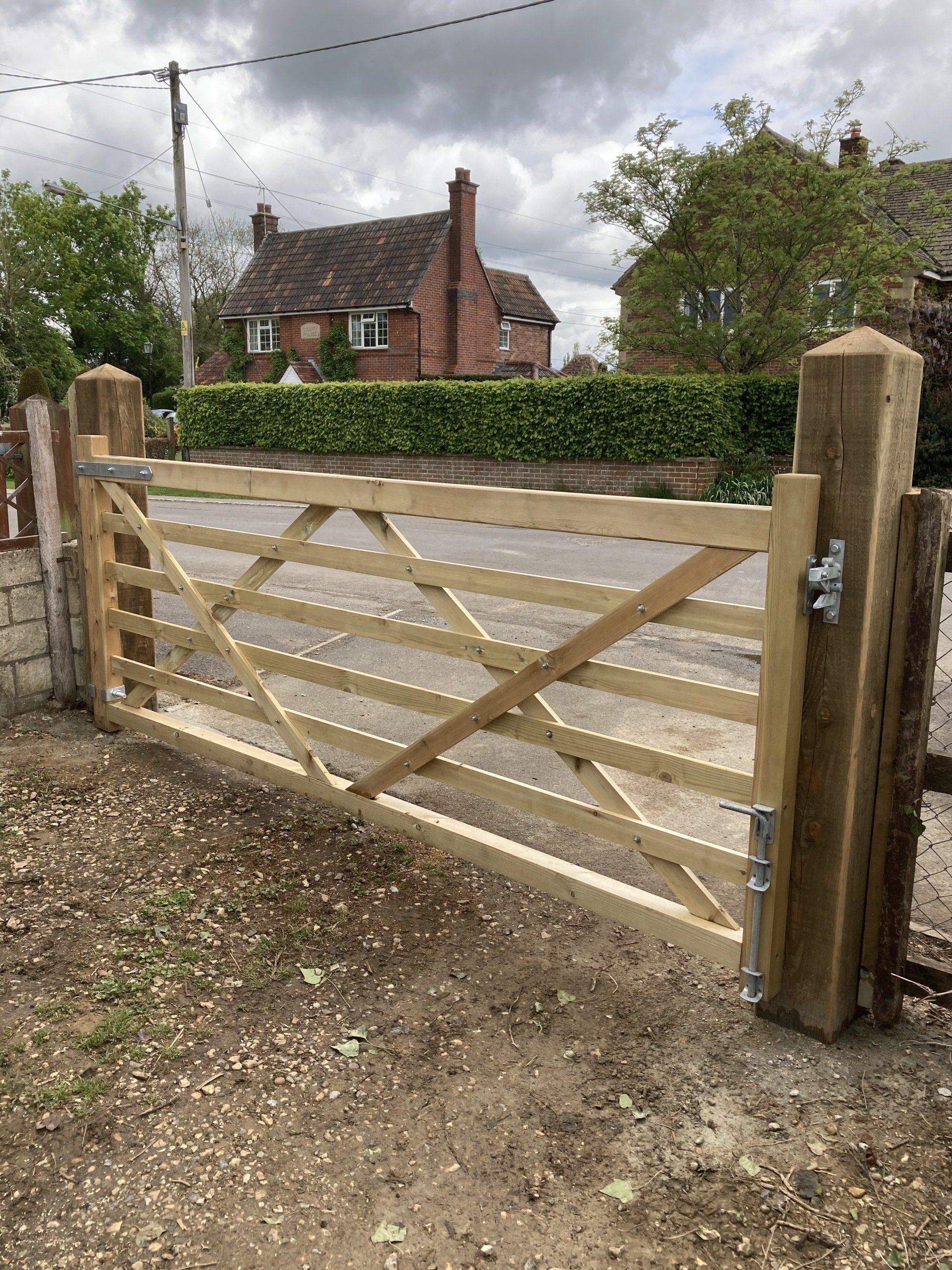 A wooden gate is sitting in the dirt in front of a house.