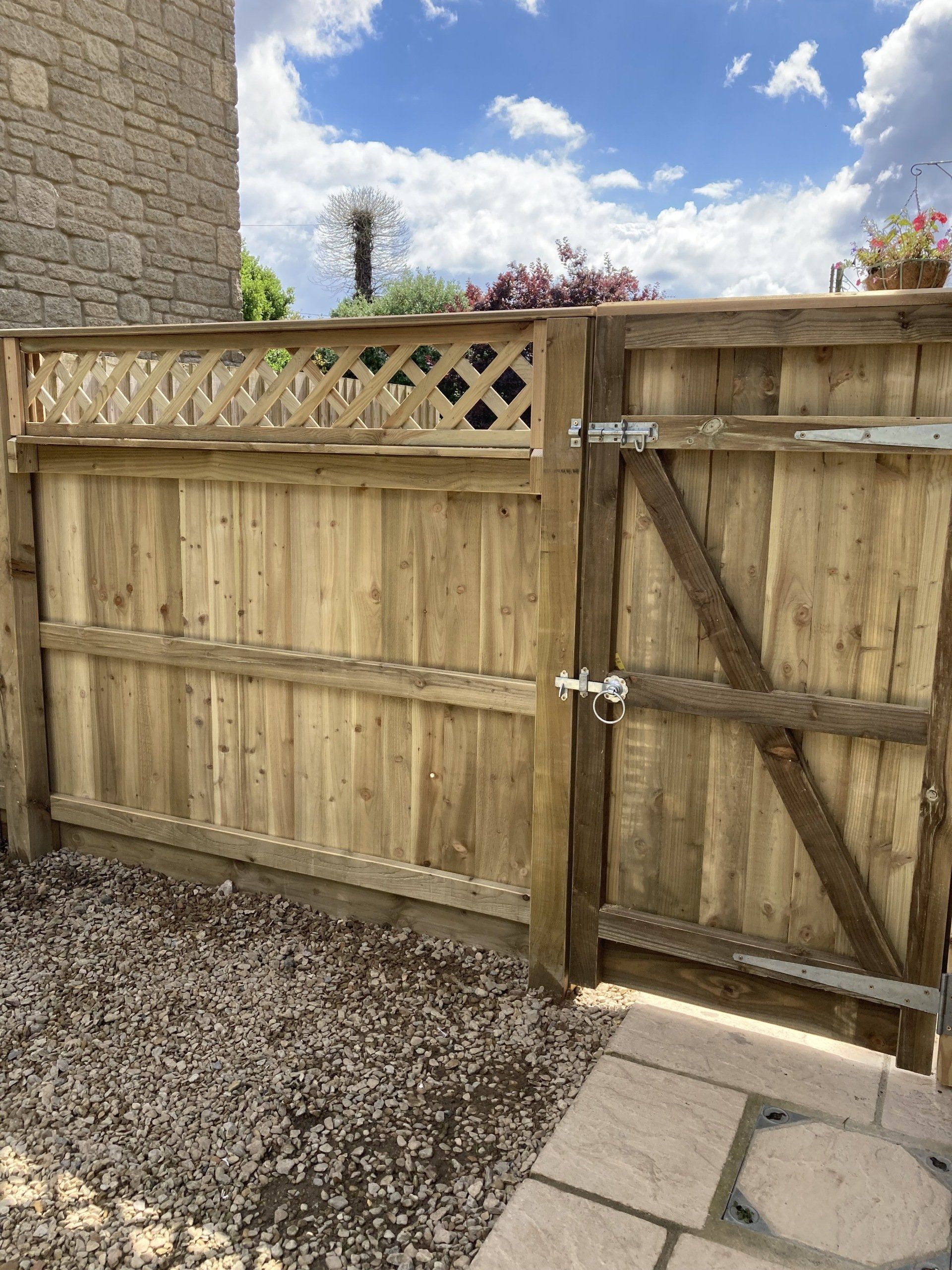 A wooden fence with a gate in front of a stone building.