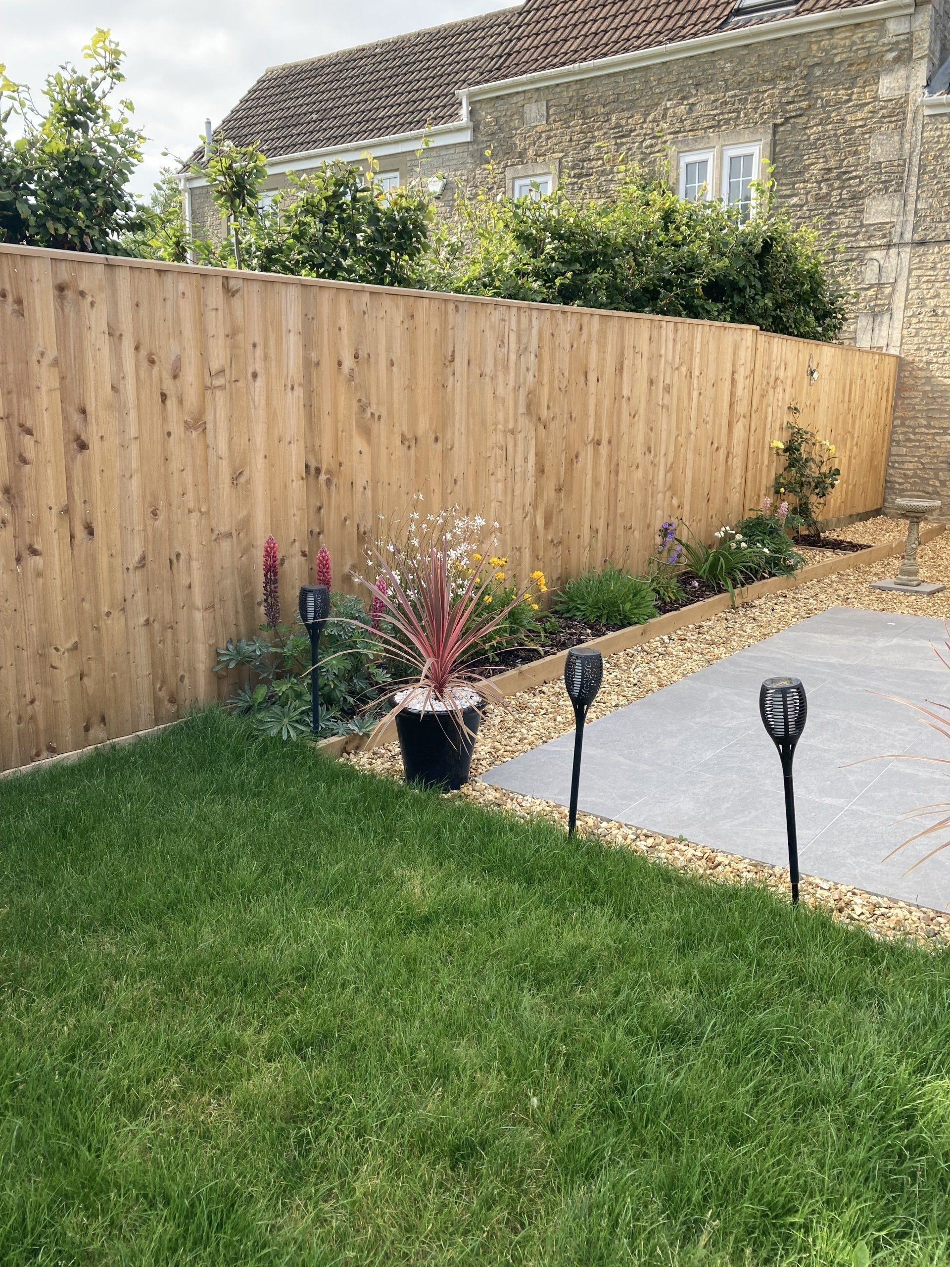 A wooden fence surrounds a lush green lawn in a backyard.