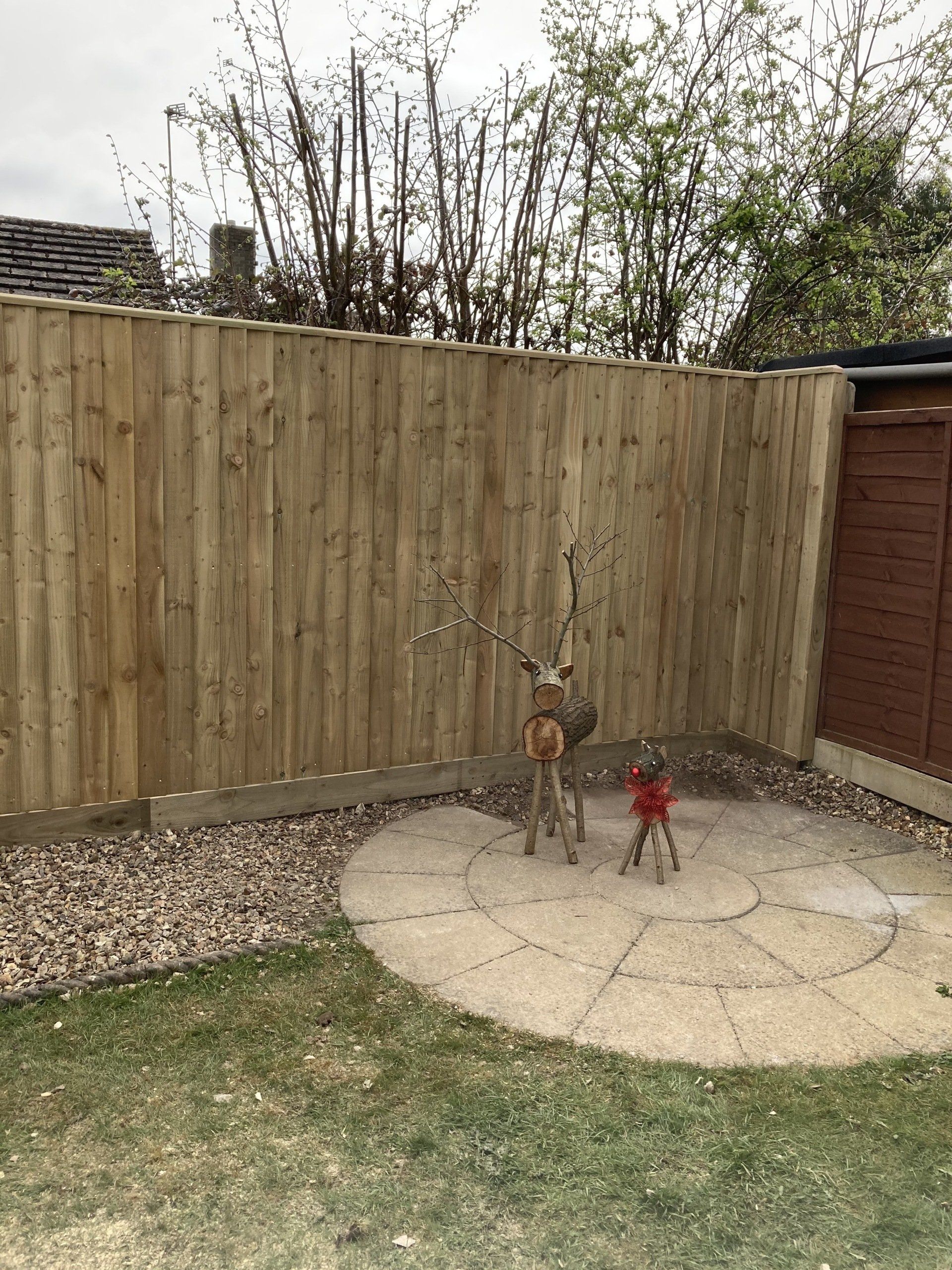 A wooden fence with a deer statue in the middle of it.