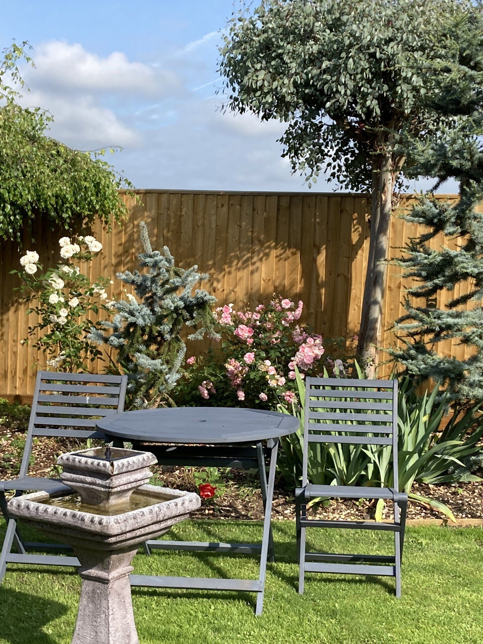 A garden with a table and chairs and a fountain.