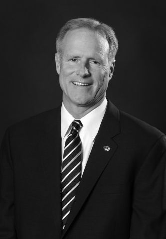 A man in a suit and tie is smiling in a black and white photo.