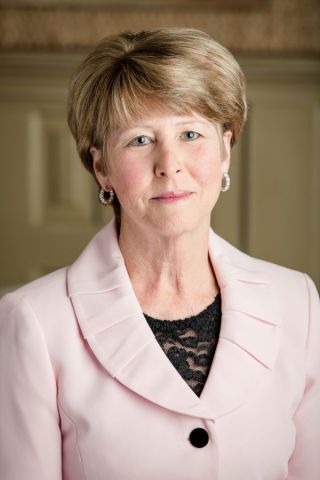 A woman is wearing a pink jacket and earrings.
