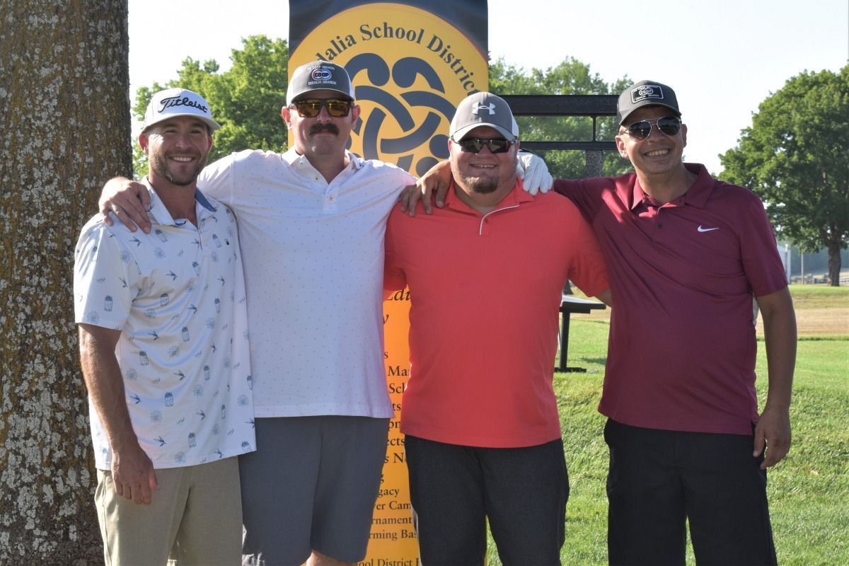 Four men are posing for a picture in front of a sign that says valley school district