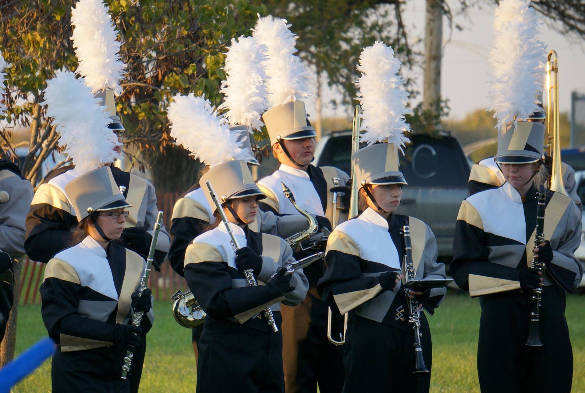 A marching band is playing instruments in a field.
