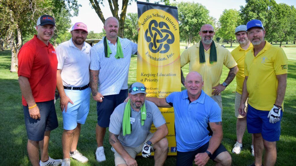 A group of men are posing for a picture on a golf course.